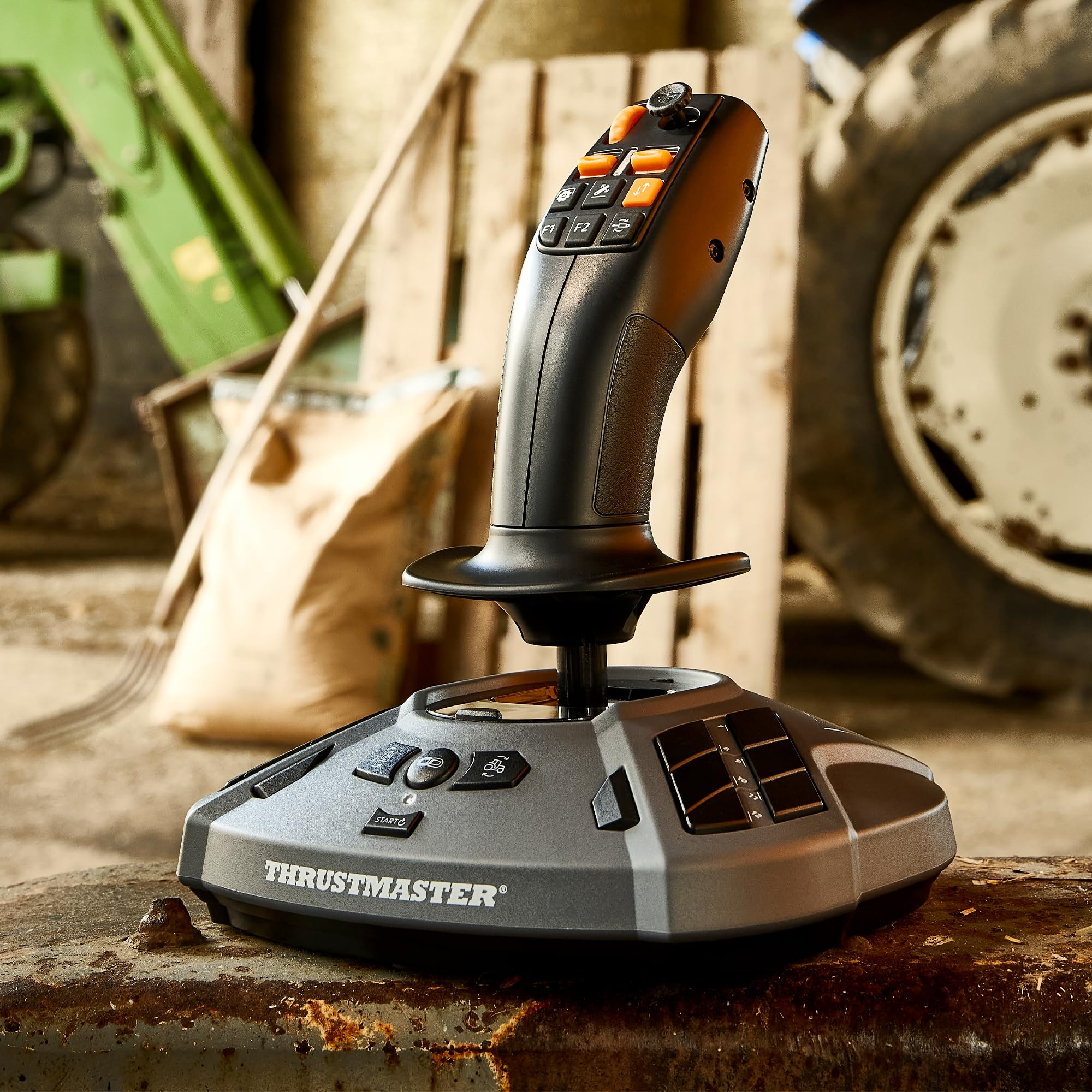 Een zwarte Thrustmaster joystick met oranje knoppen staat op een roestige metalen standaard.