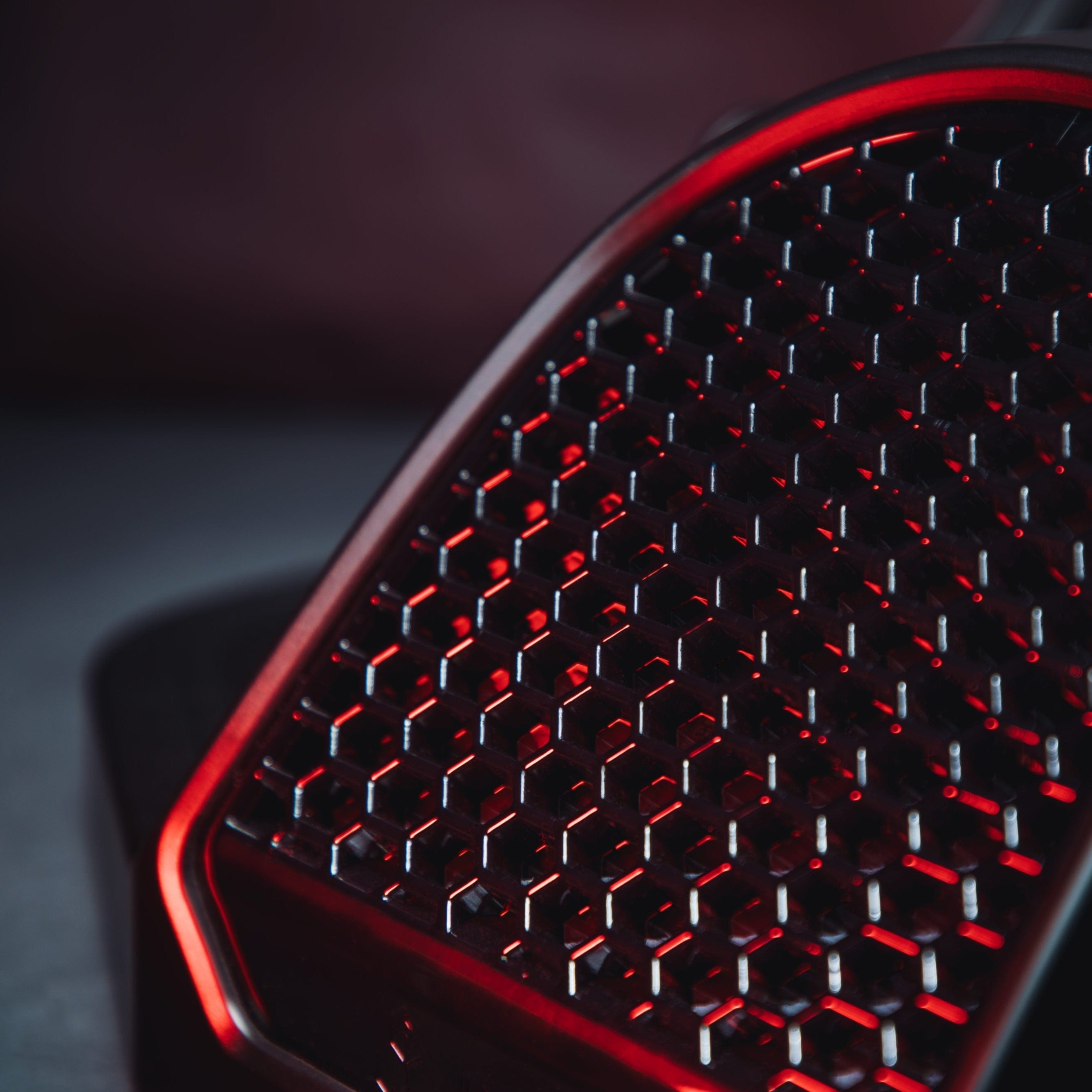 Close-up of a black honeycomb pattern with red illumination.