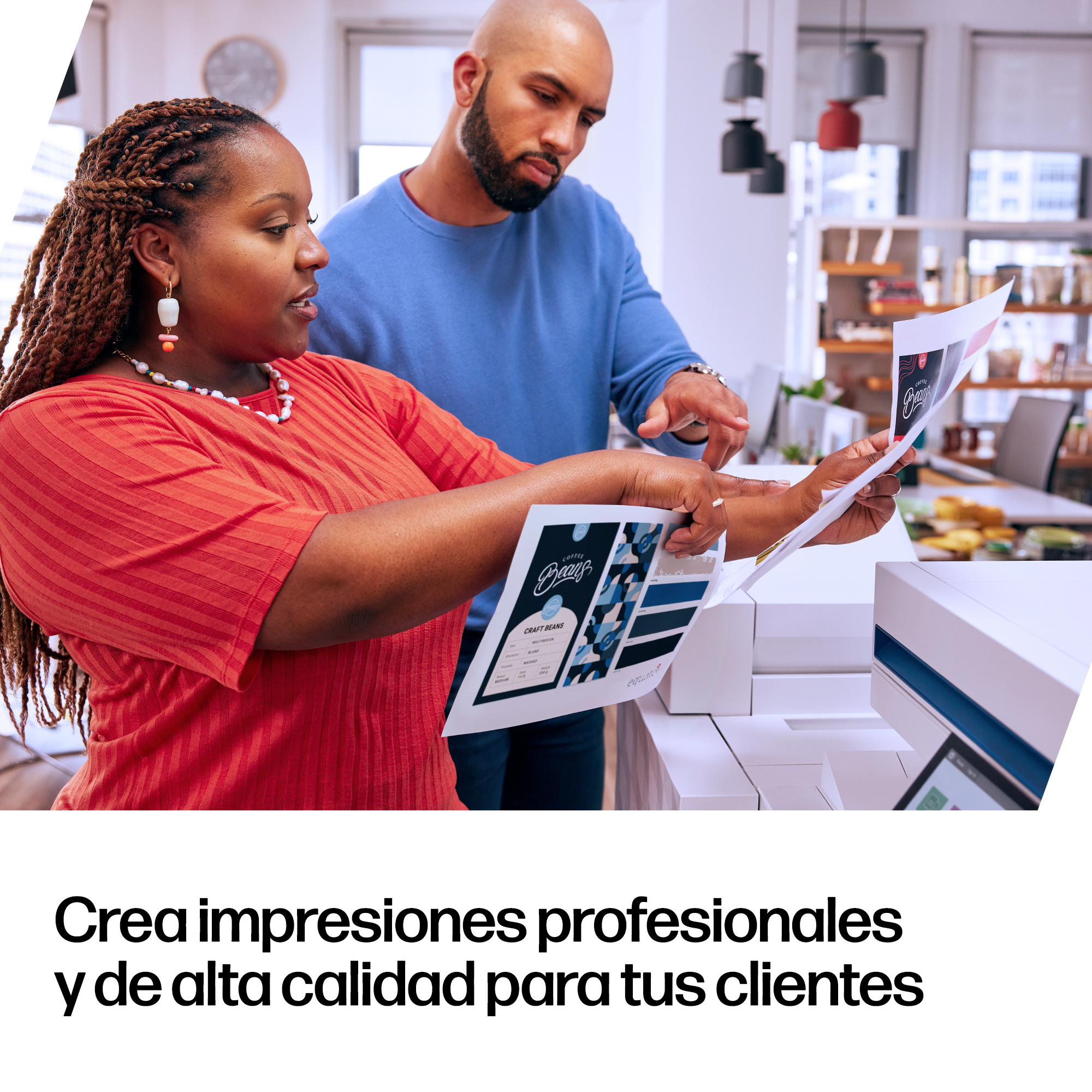 Man and woman review prints near printer. Man in blue, woman in red.