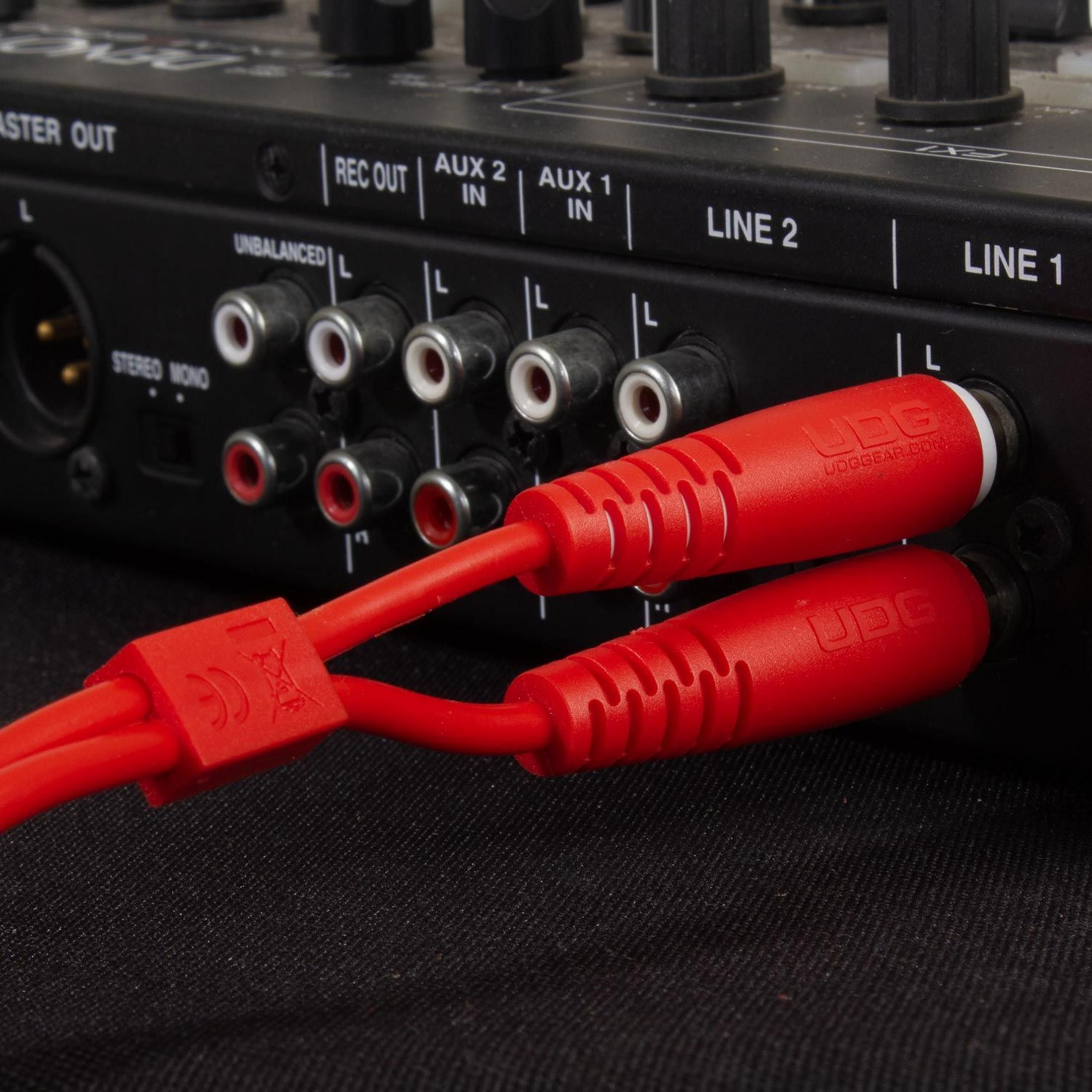 Zwei rote Kabel sind in einen schwarzen Audio-Mixer eingesteckt.