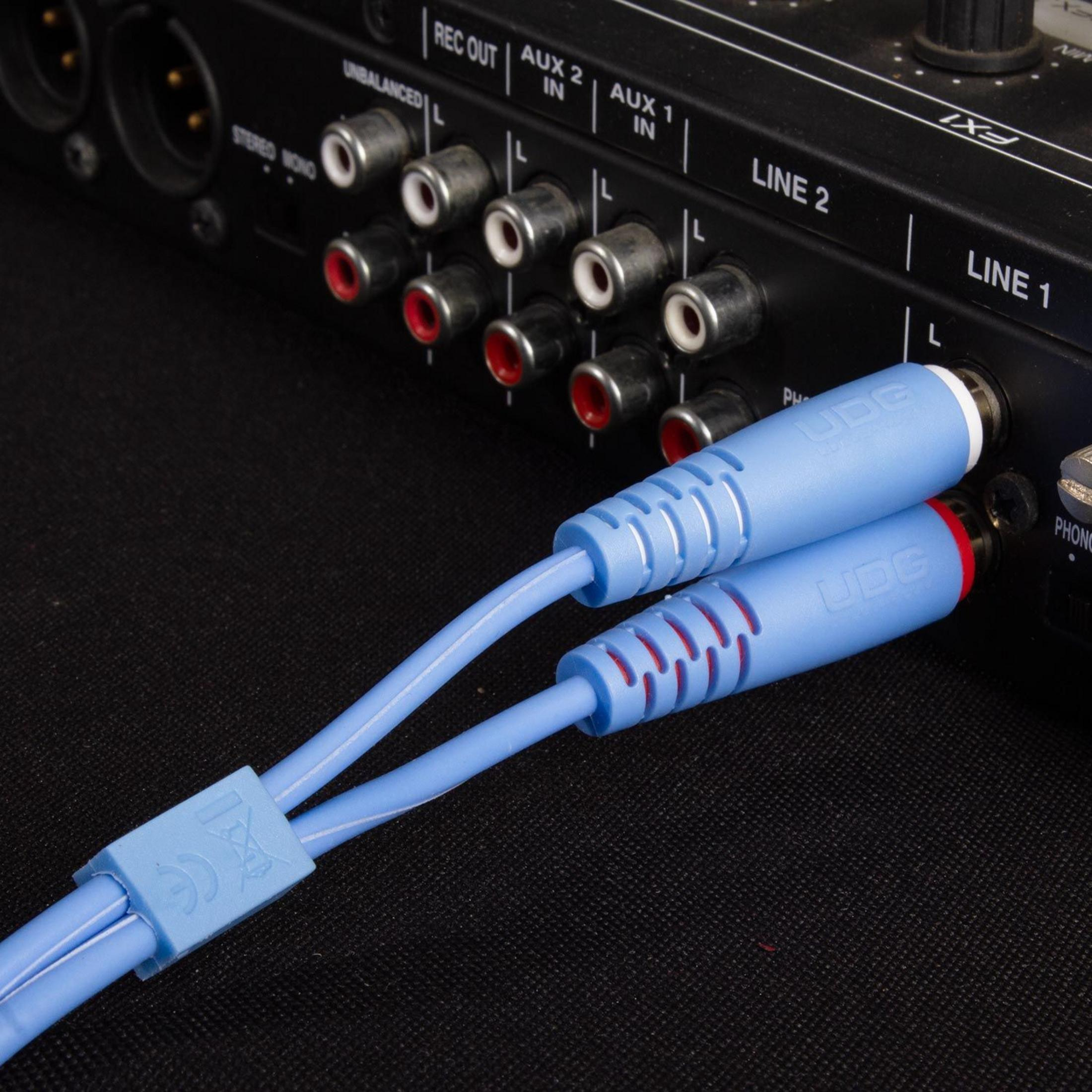 Zwei blaue Audiokabel verbinden sich mit einem schwarzen Mischpult mit Cinch-Anschlüssen.