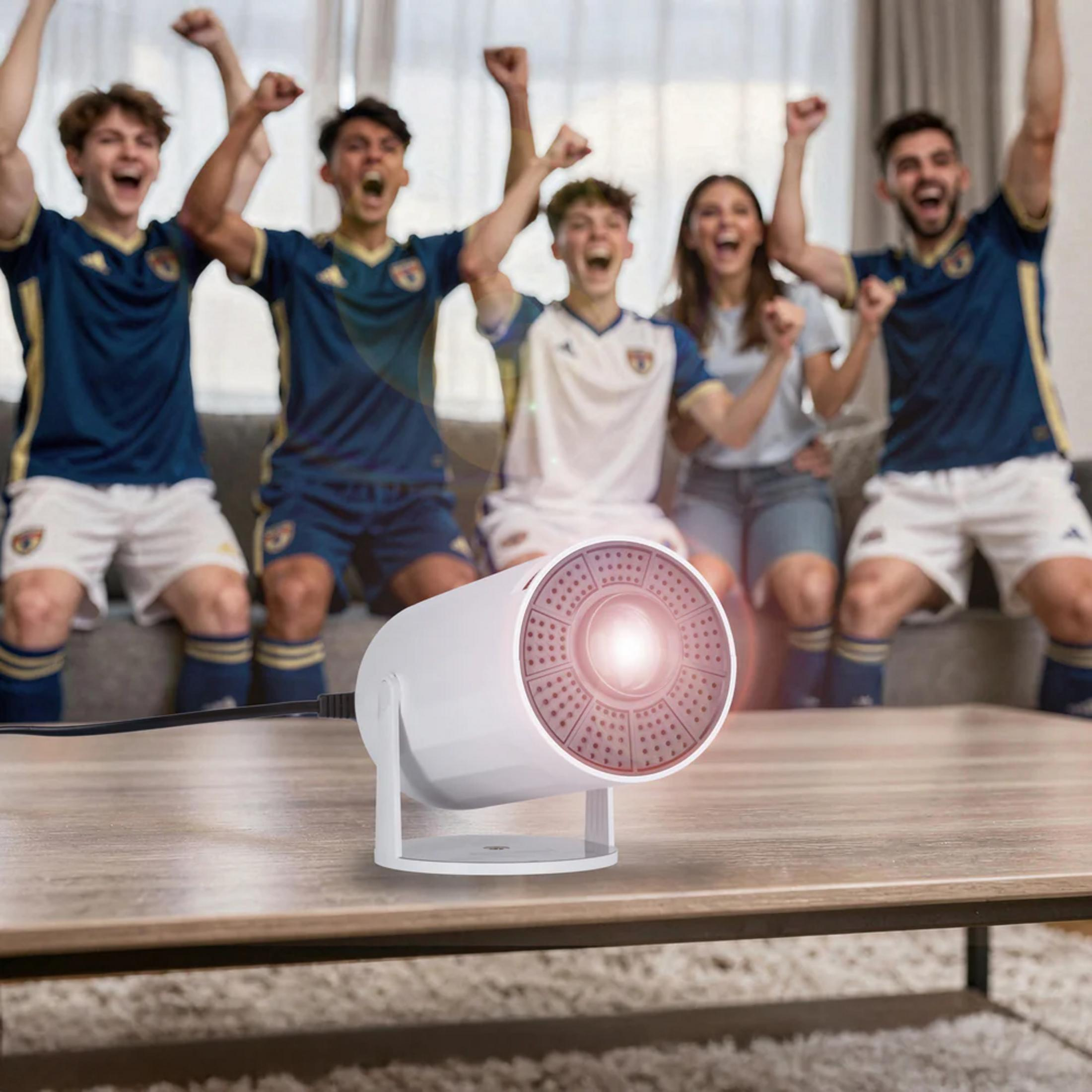 Fußballfans jubeln vor einem weißen Projektor auf einem Holztisch.