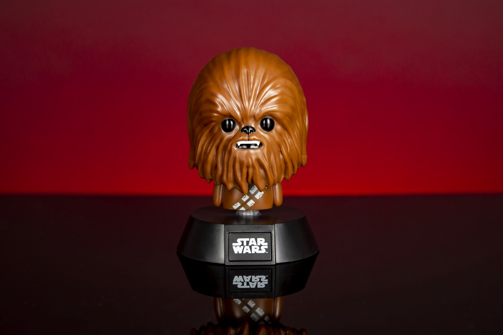 Brązowa figurka Chewbakki z logo Star Wars na czarnej podstawie.
