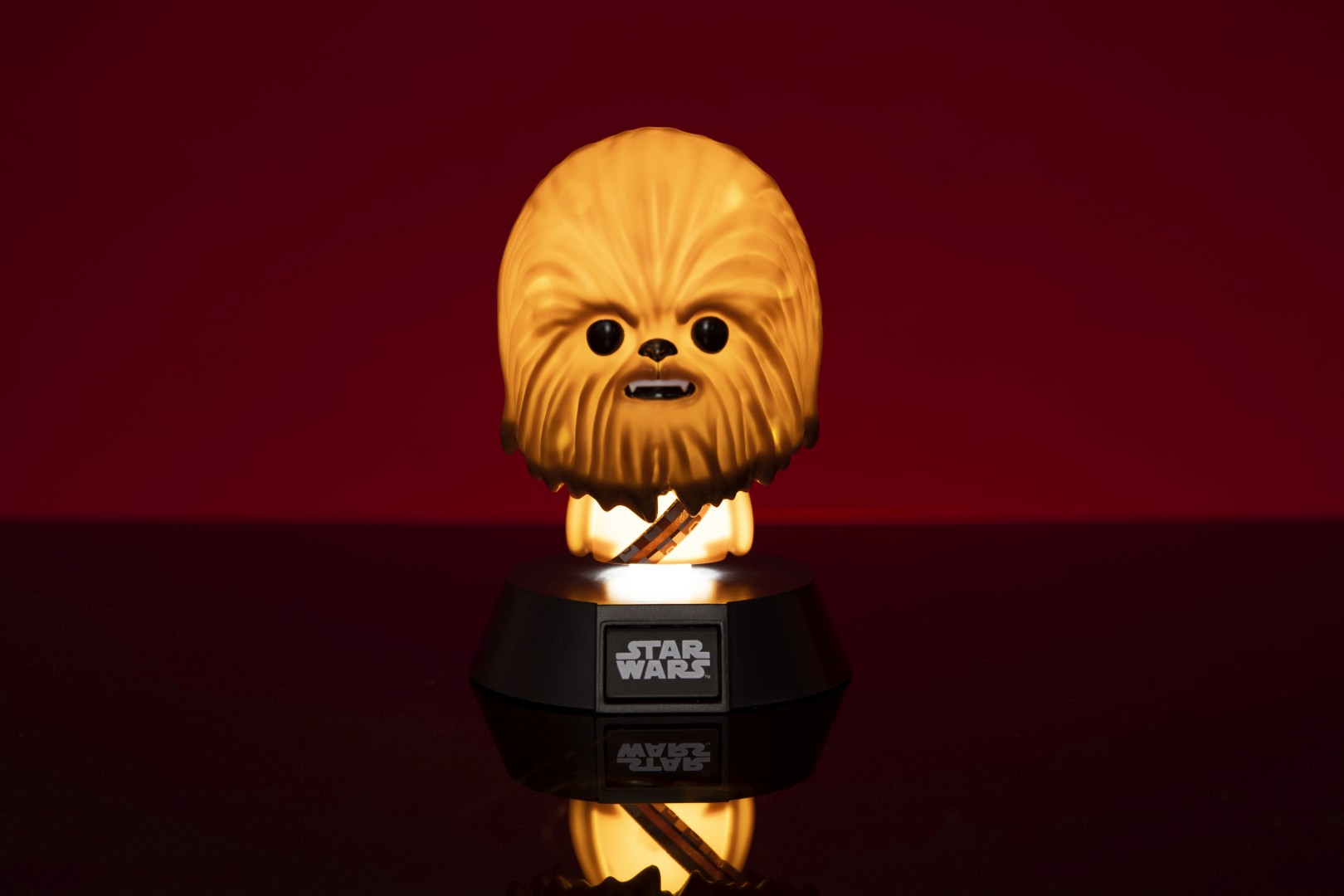 Podświetlana figurka Chewbacci z logo Star Wars na czarnej podstawie.