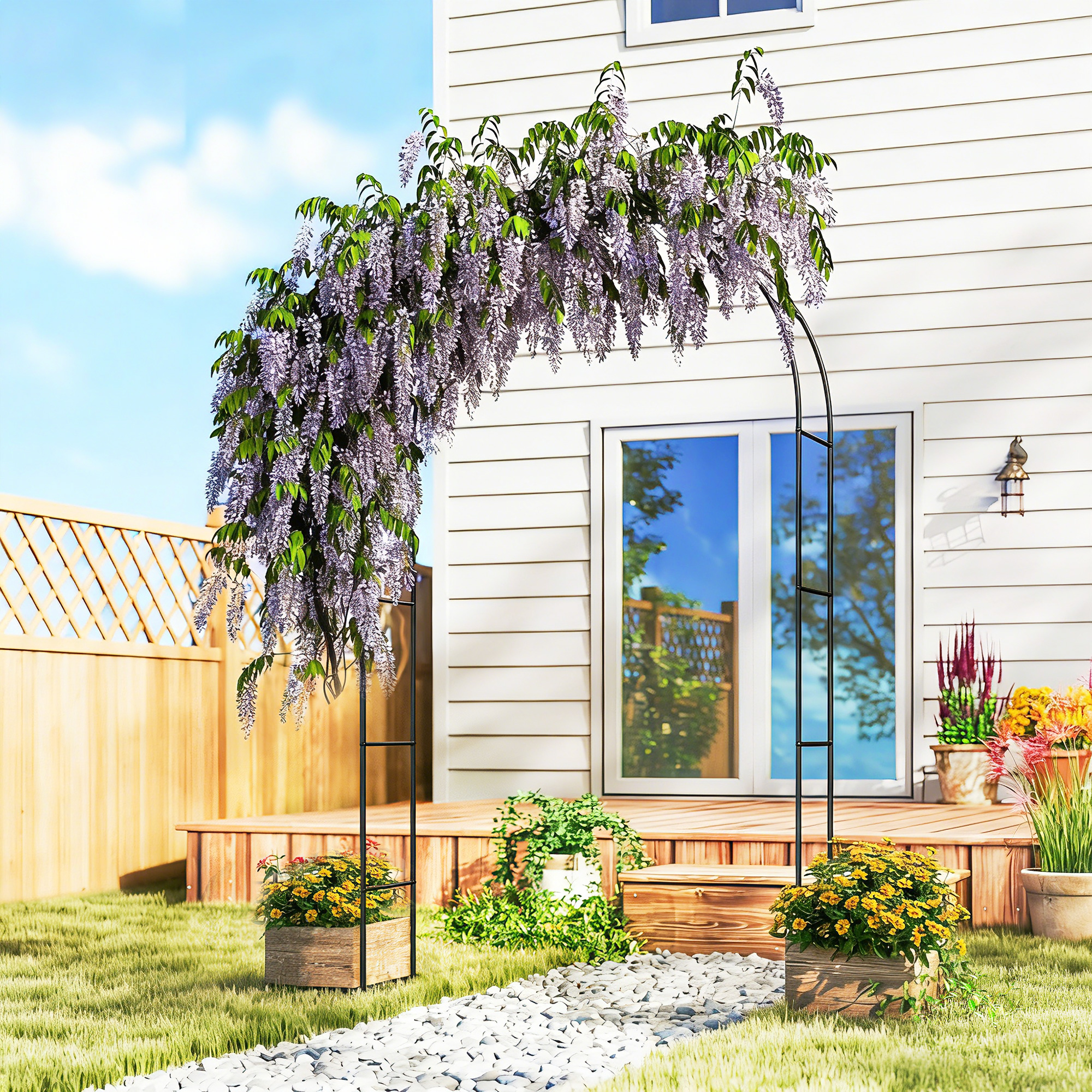 Un arco da giardino coperto di glicine viola davanti a una casa bianca.