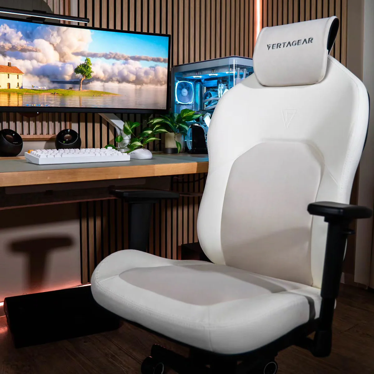 Silla gamer blanca frente a un escritorio con computadora y monitor.