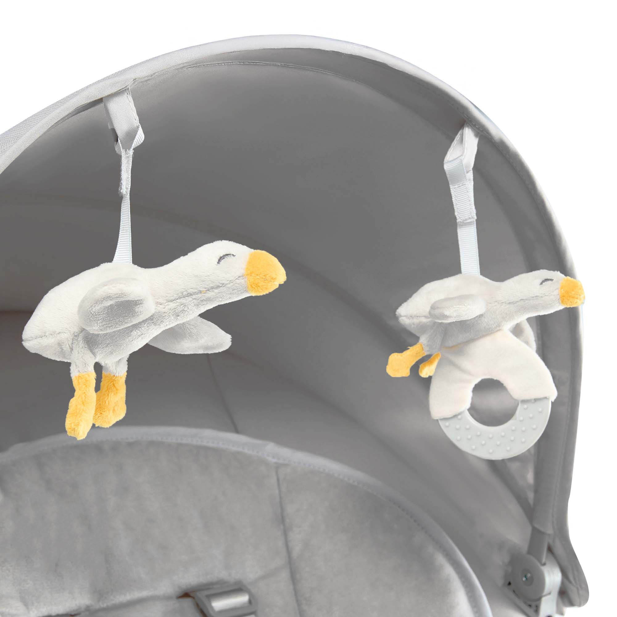 Zwei Plüschtier-Gänse mit gelben Schnäbeln und Füßen hängen an einem Kinderwagen.