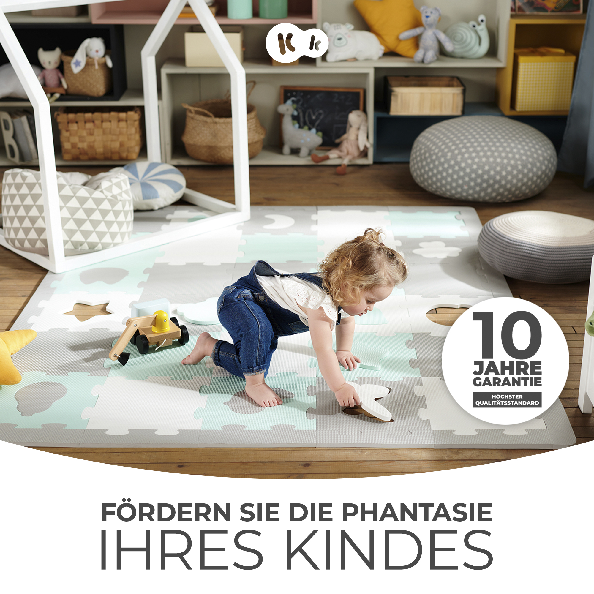 Ein Kleinkind krabbelt auf einer Spielmatte mit einem Holzbagger und Spielzeug.