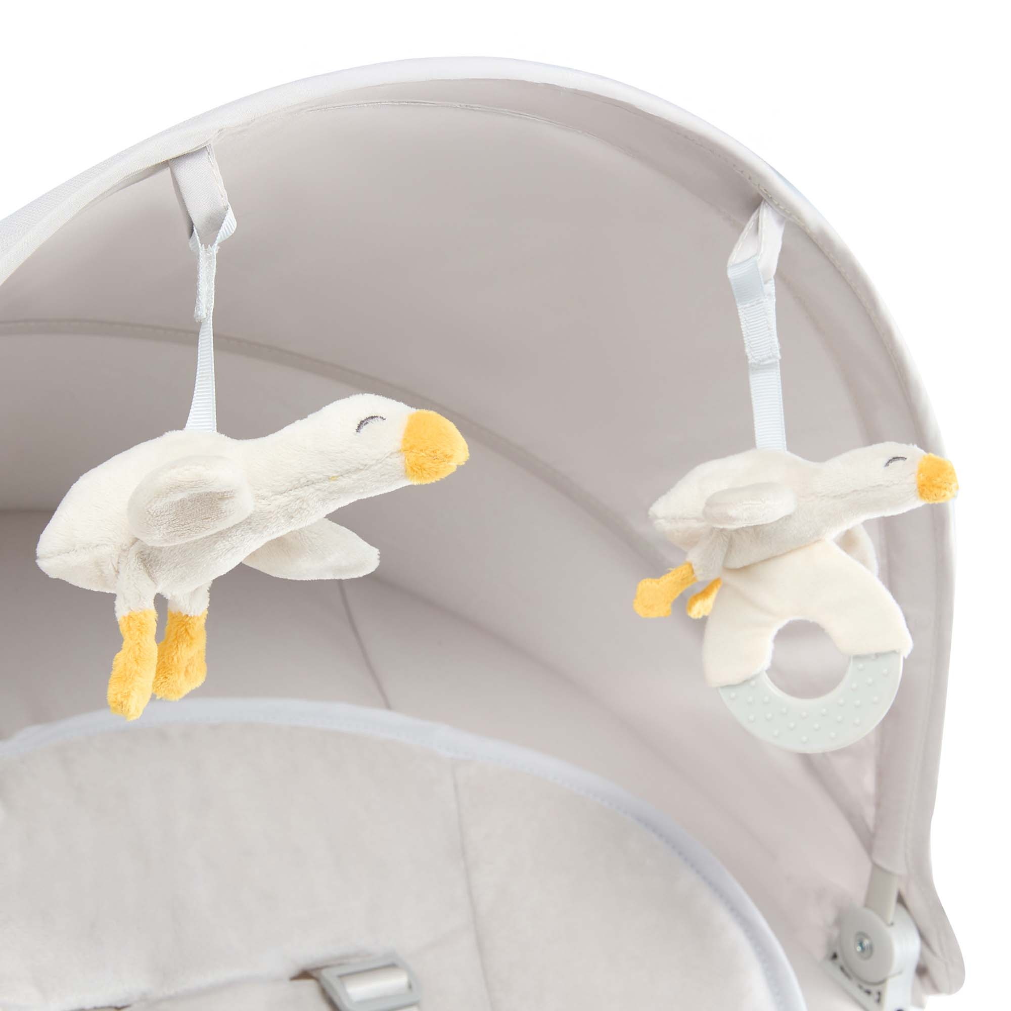 Zwei Stoffgänse mit gelben Füßen hängen an einem Kinderwagen.
