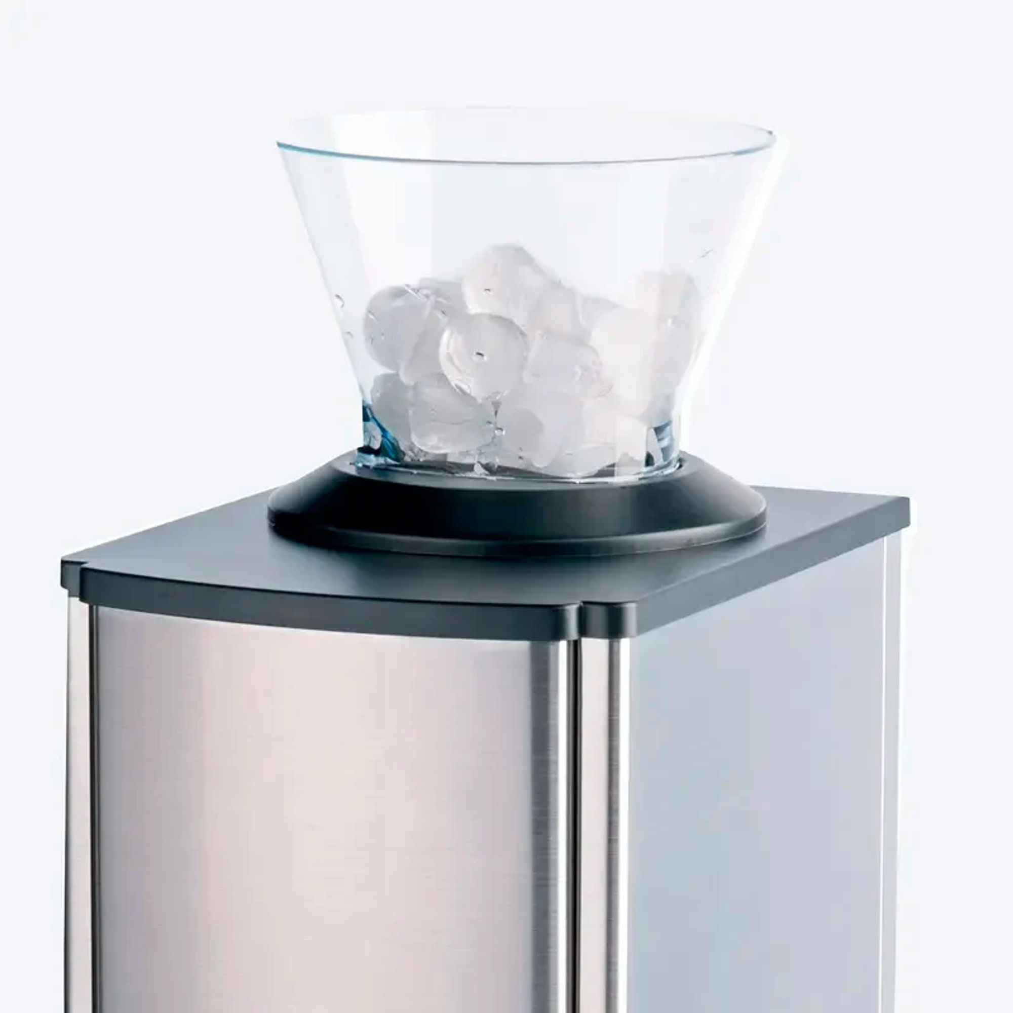 A glass container filled with ice cubes sits atop a silver appliance.