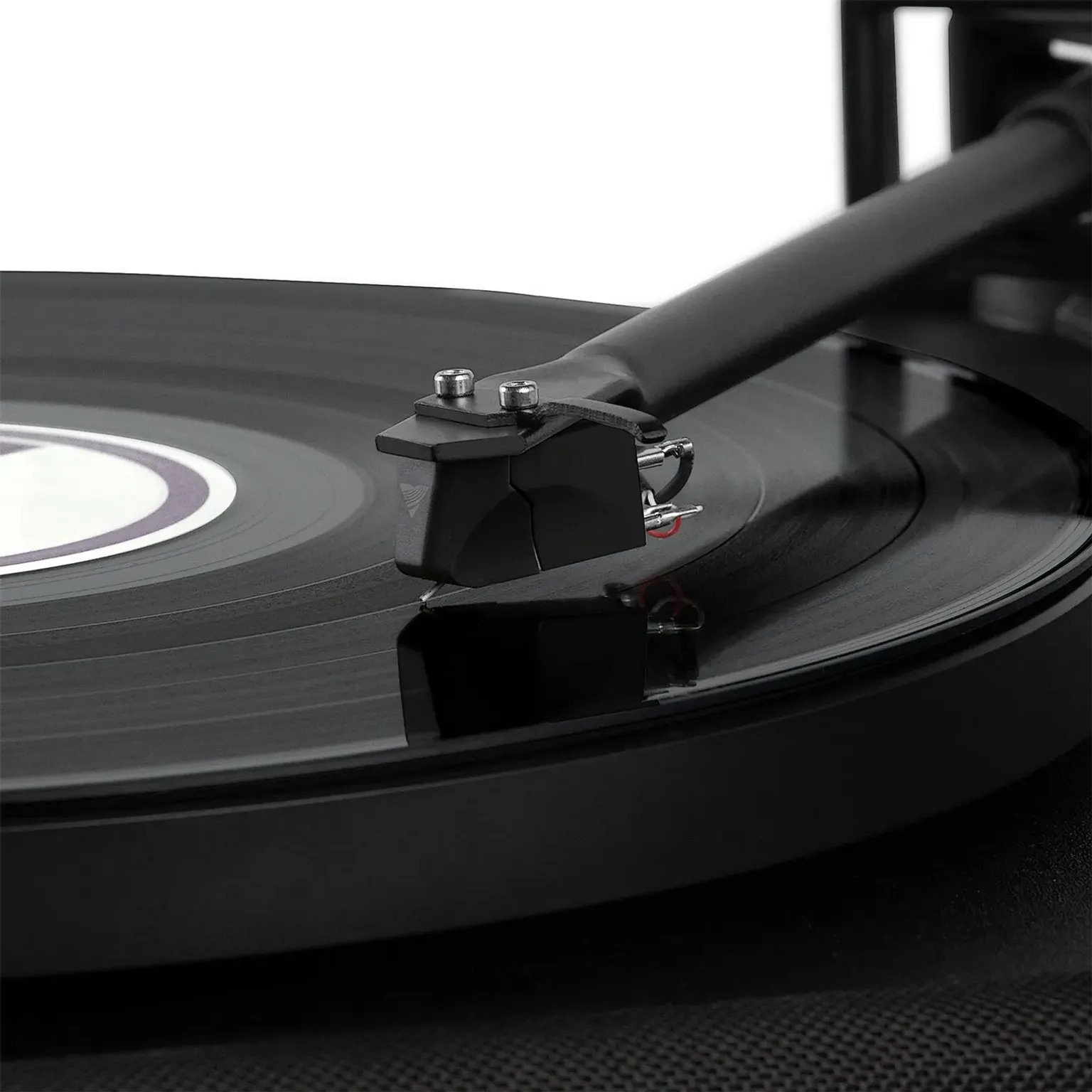 Gros plan d'une aiguille de tourne-disque noire sur un disque vinyle en rotation.