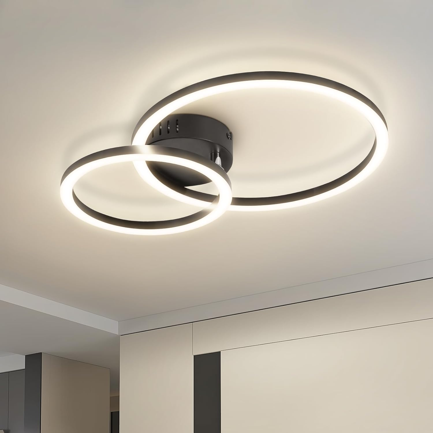 Moderne Deckenleuchte mit zwei ineinandergreifenden schwarzen Ringen, beleuchtet mit weißen LEDs.