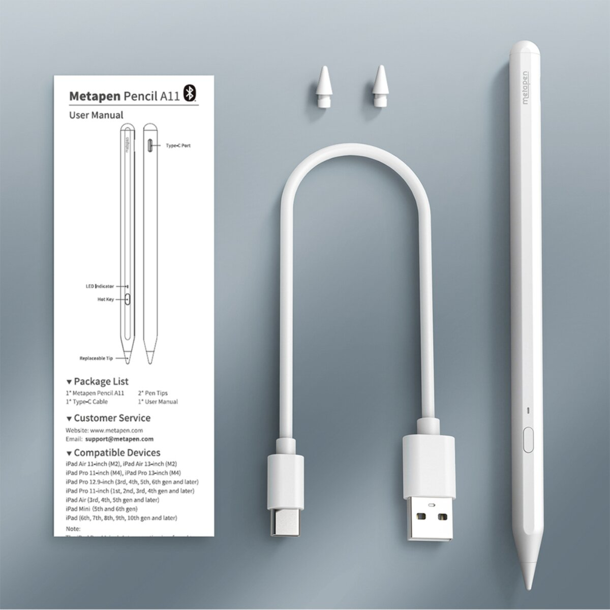 Ein weißer Stift, zwei Spitzen, ein Ladekabel und eine Anleitung sind auf grauem Hintergrund angeordnet.