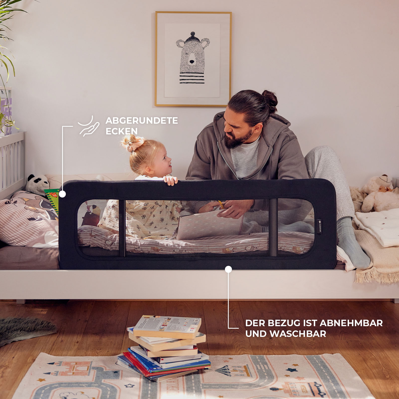 Ein Mann und ein Kind auf einem Bett mit einem Bettgitter. Oben ist ein Bild.