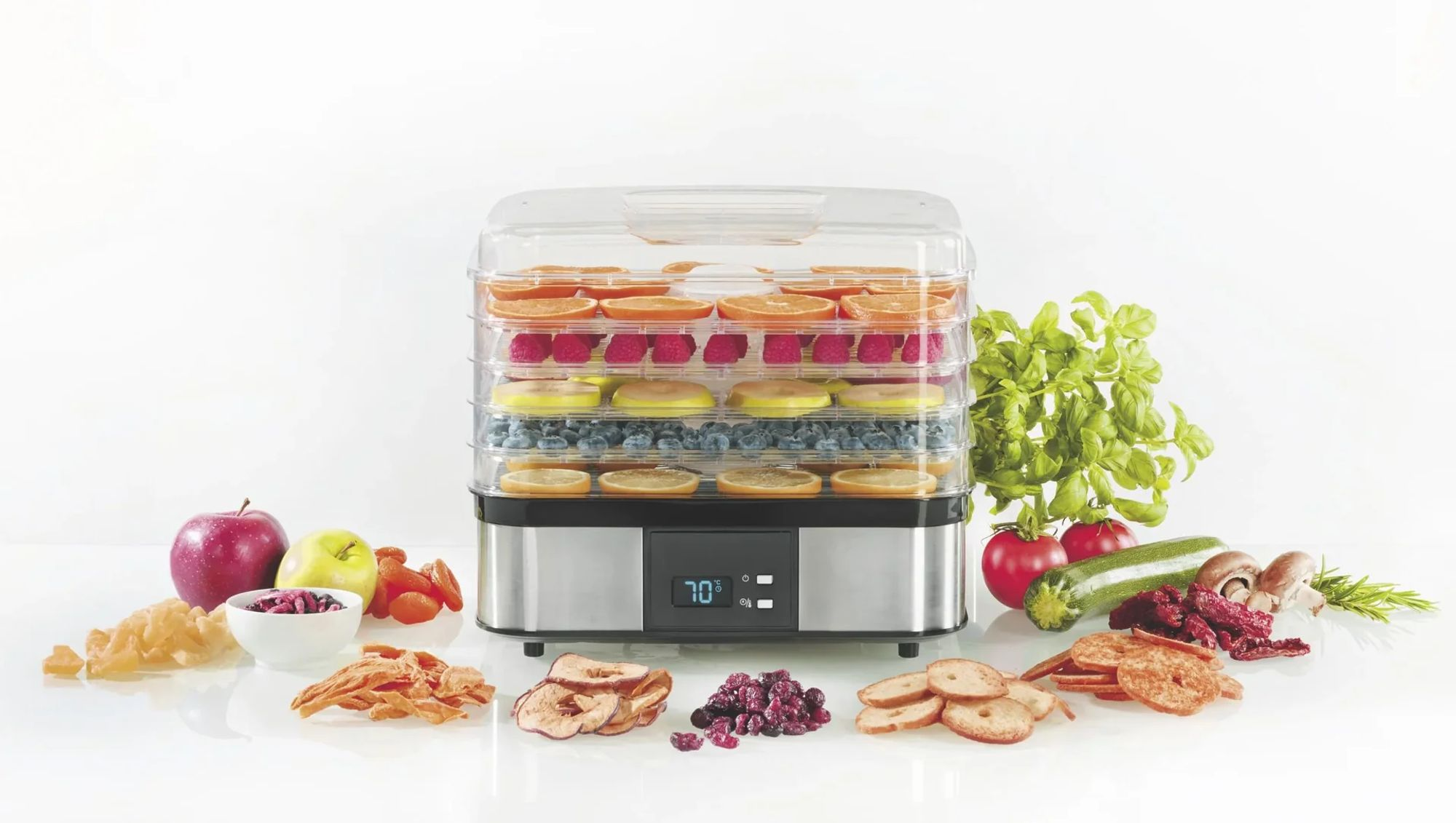 Un essiccatore alimentare a più livelli con frutta e verdura, circondato da frutta secca.