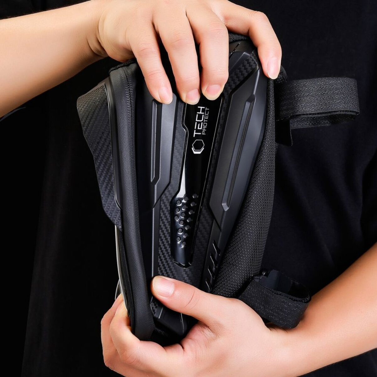 Guardia de brazo blindado negro con logo Tech Protect, sostenido por manos.