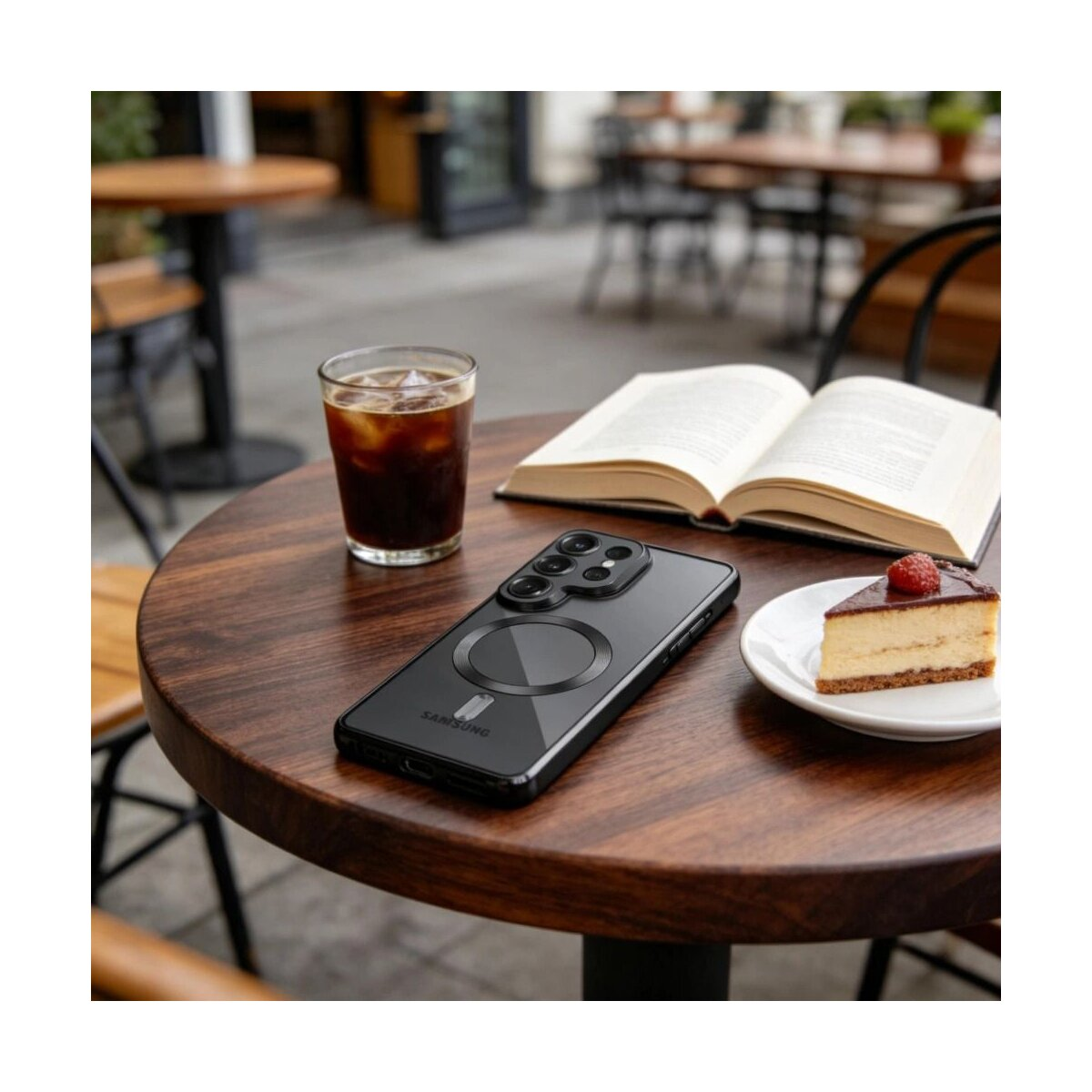 Ein Smartphone, ein Buch, Kaffee und Kuchen auf einem Holztisch im Freien.