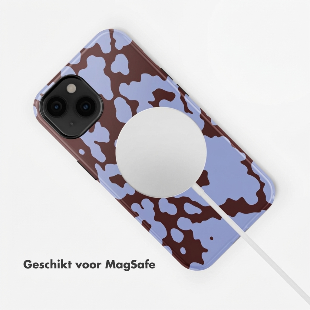 Un telefono con cover a stampa mucca marrone e blu e cavo di ricarica MagSafe.