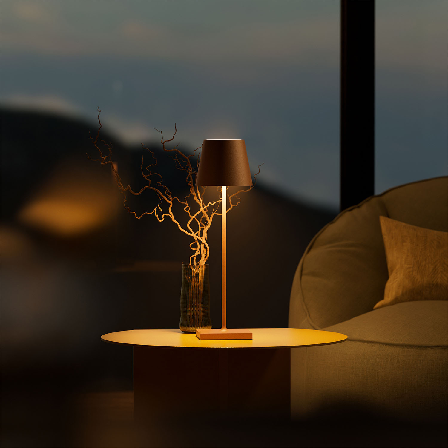 Ein Tisch mit Lampe, Vase und Zweigen vor einem Fenster mit Blick auf Berge.
