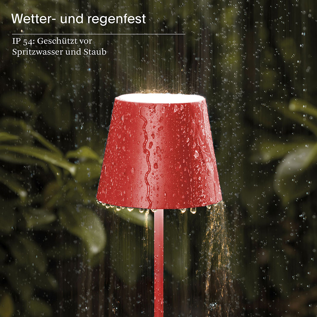 Rote Lampe im Regen, mit Wassertropfen auf dem Schirm und Sprühwasser.