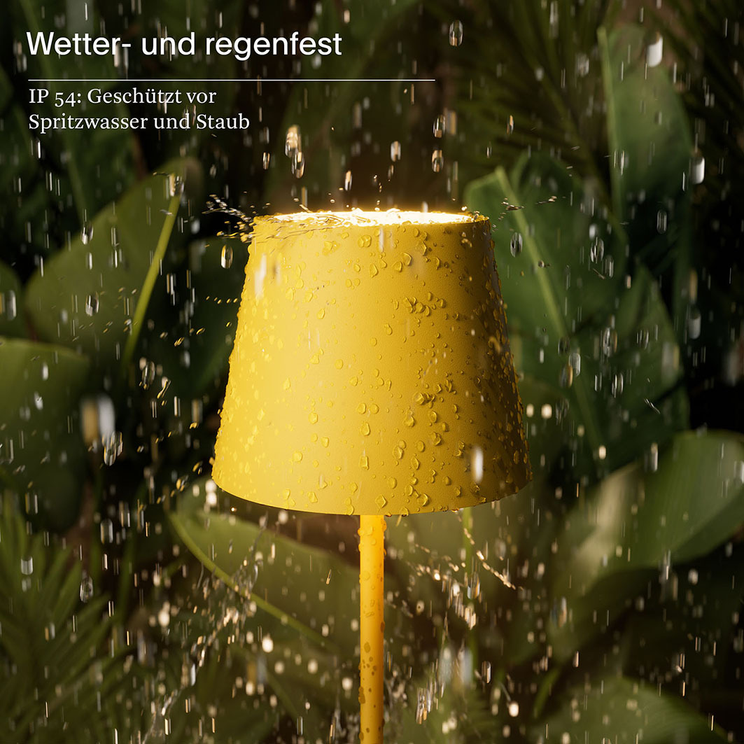 Eine gelbe Lampe steht im Regen, Wassertropfen auf der Oberfläche. Üppiges grünes Laub im Hintergrund.