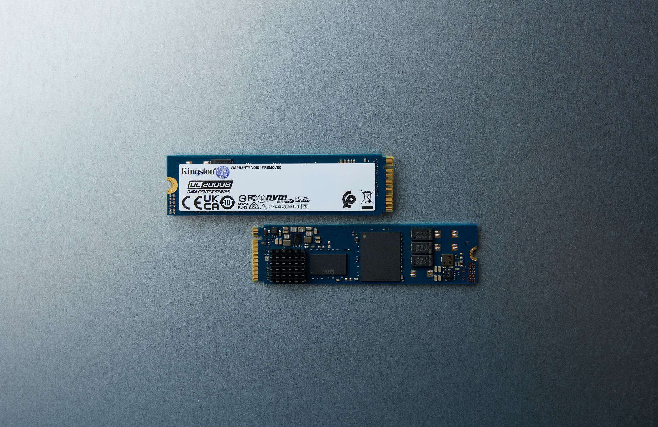 Dos SSDs M.2 Kingston sobre fondo gris. Una orientada hacia arriba, la otra hacia abajo.