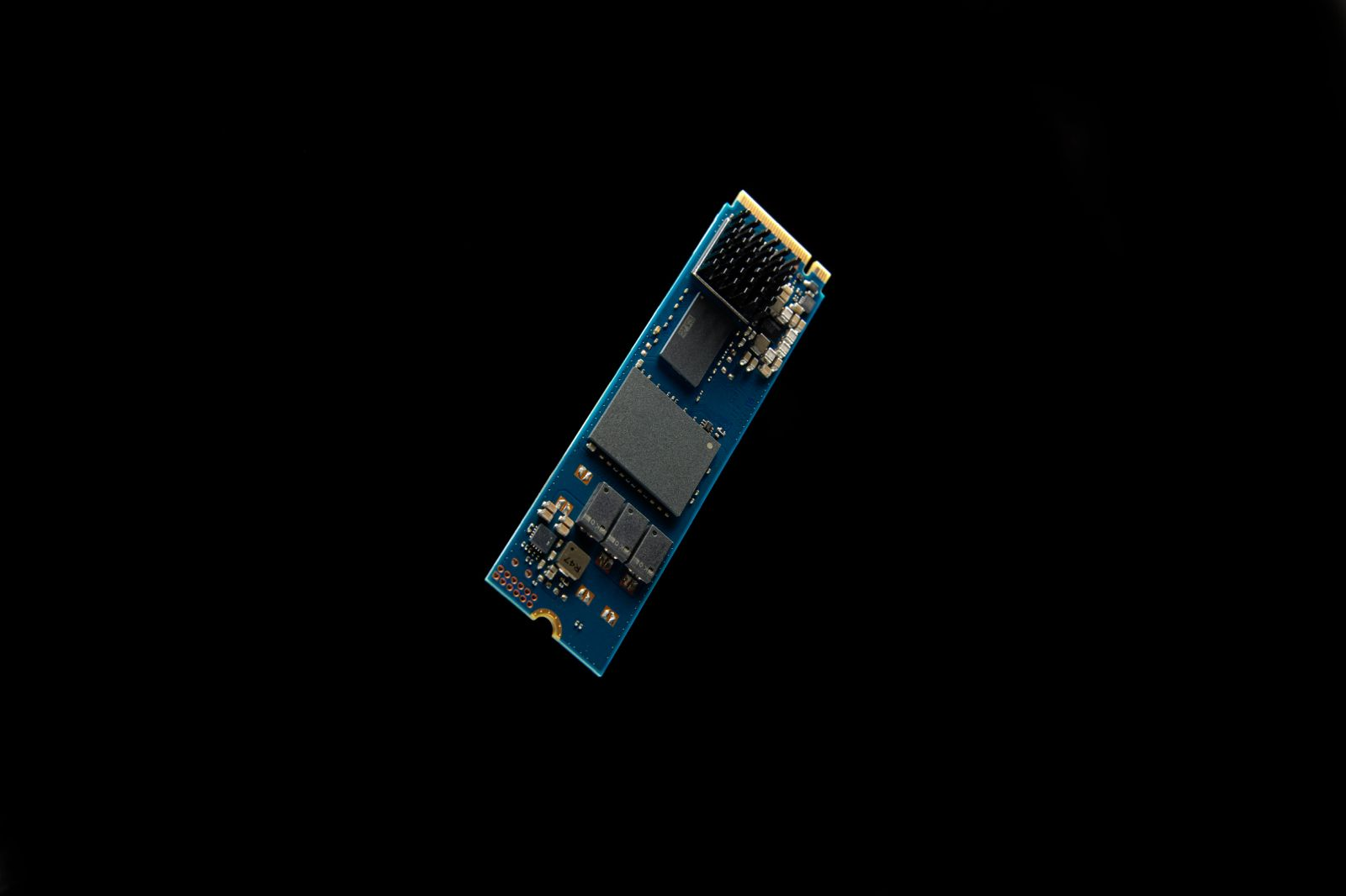 A blue circuit board with black chips and heatsinks on a black background.