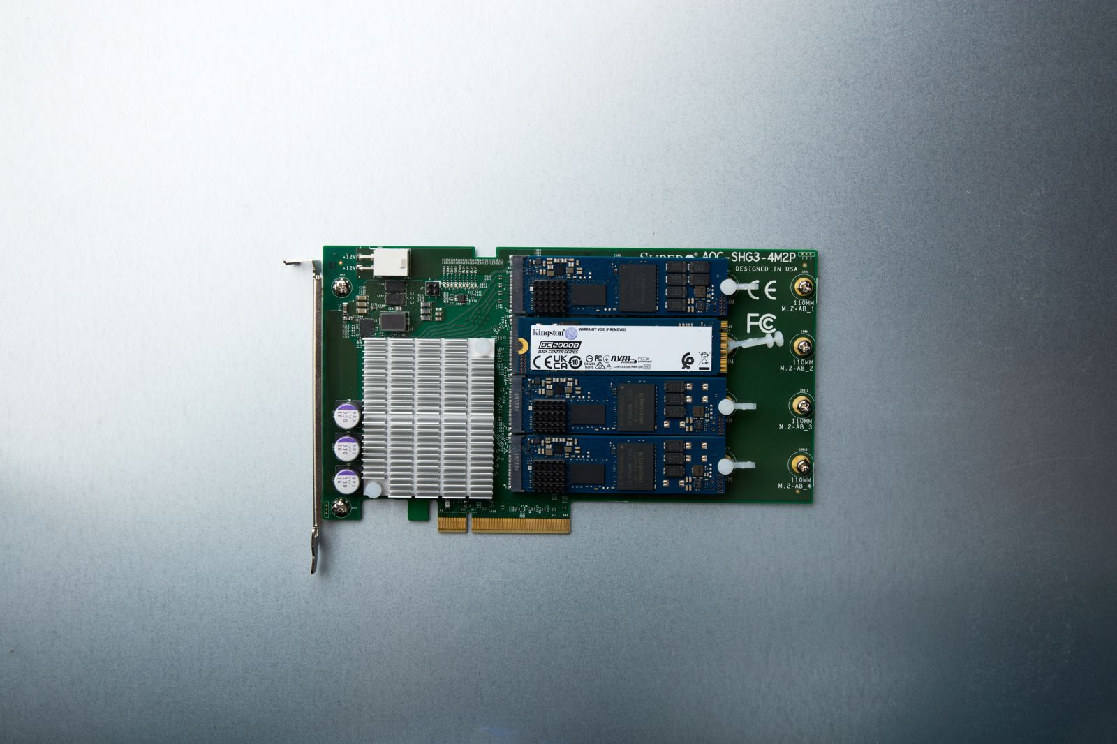 A green circuit board with three blue M.2 SSDs, heatsink, and connectors.