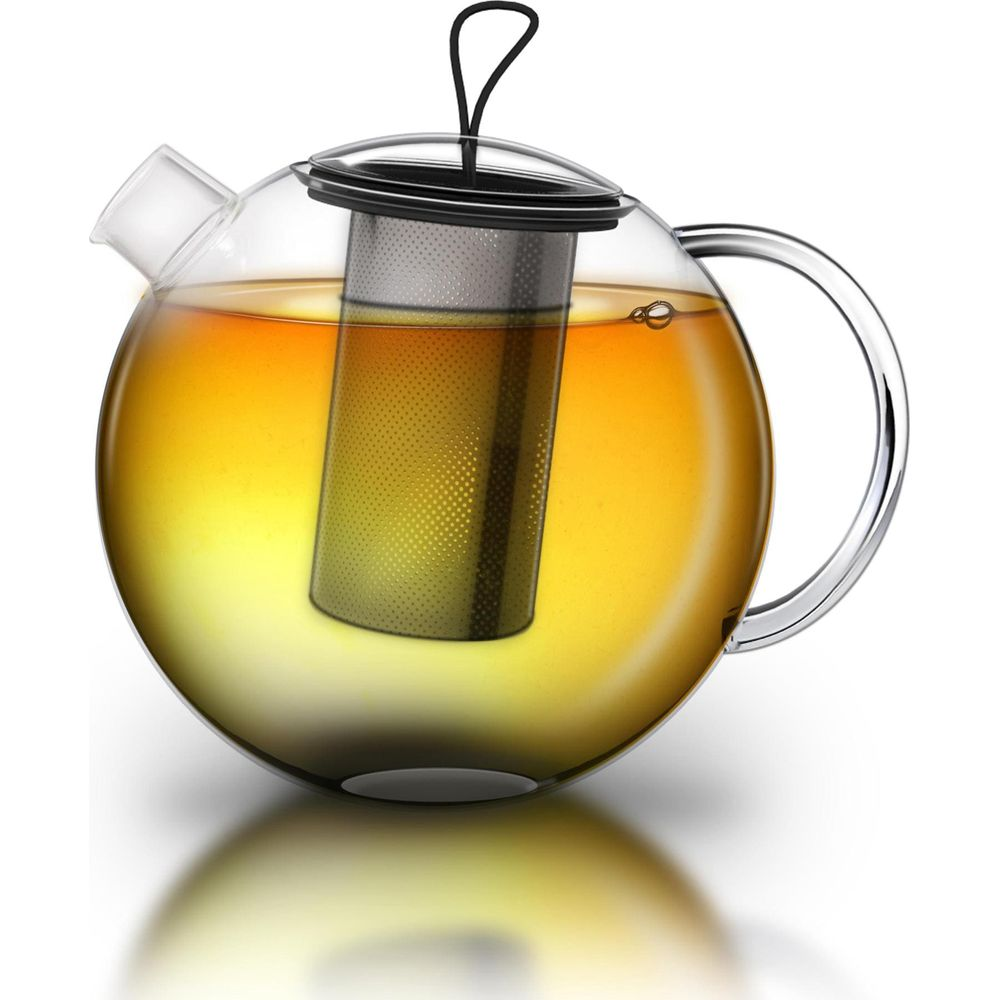 Teiera in vetro piena di tè dorato e un infusore in metallo.