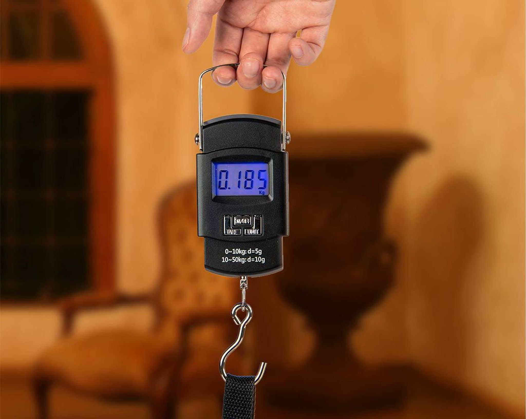 Eine Hand hält eine schwarze digitale Waage mit einem Gewicht von 0,185 kg.