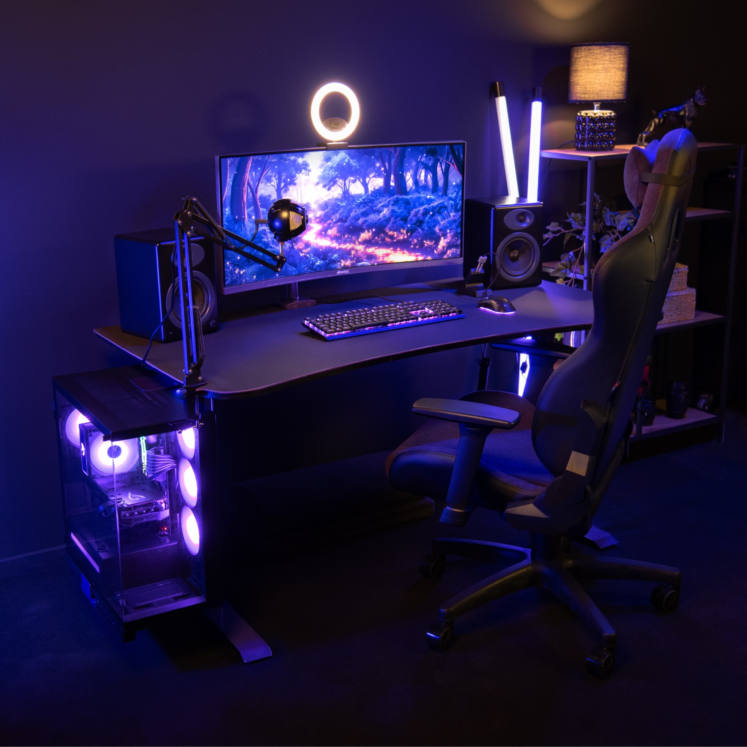 Una postazione da gioco con scrivania, sedia, PC, monitor e microfono.