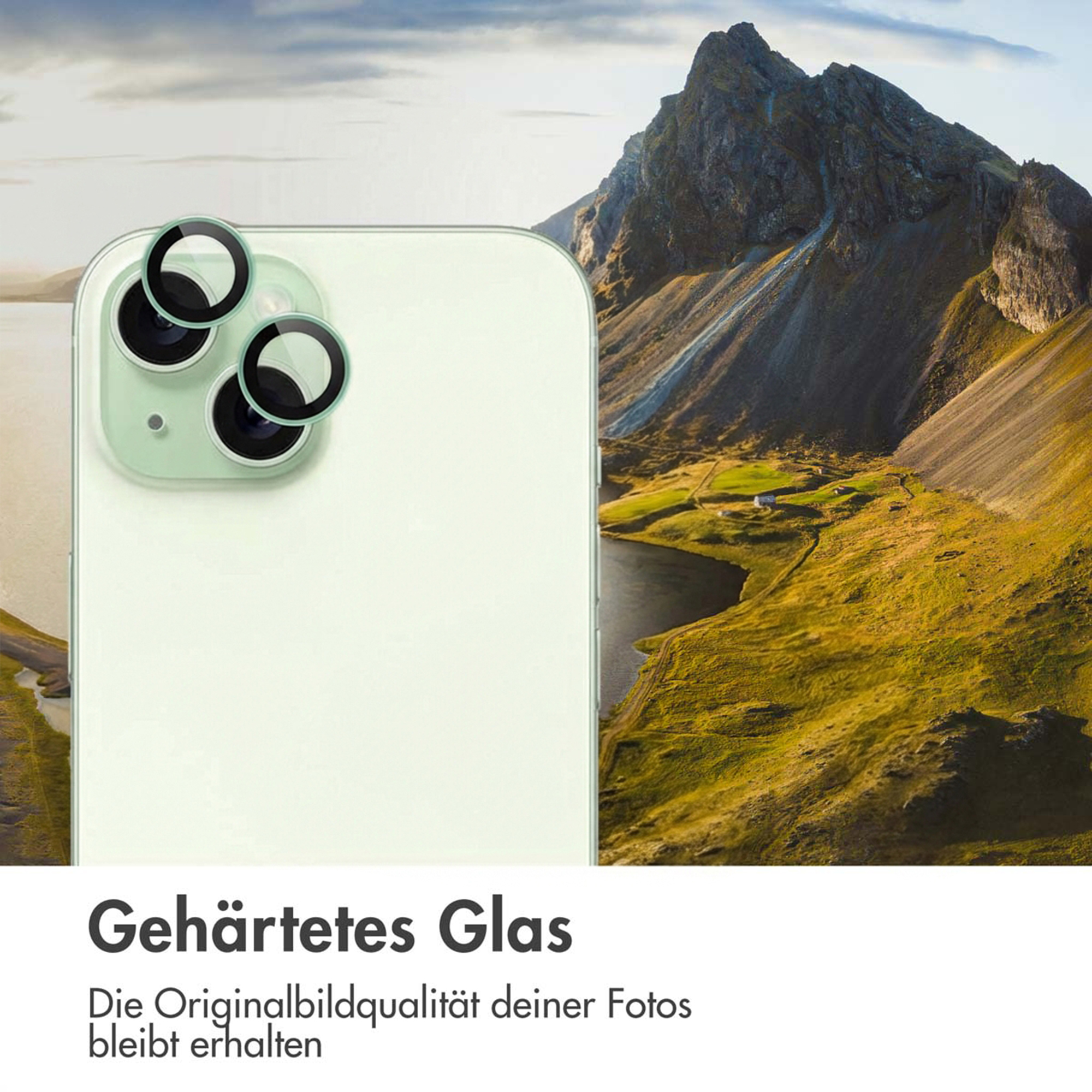 A light green smartphone with camera lens protector in front of a mountain landscape.