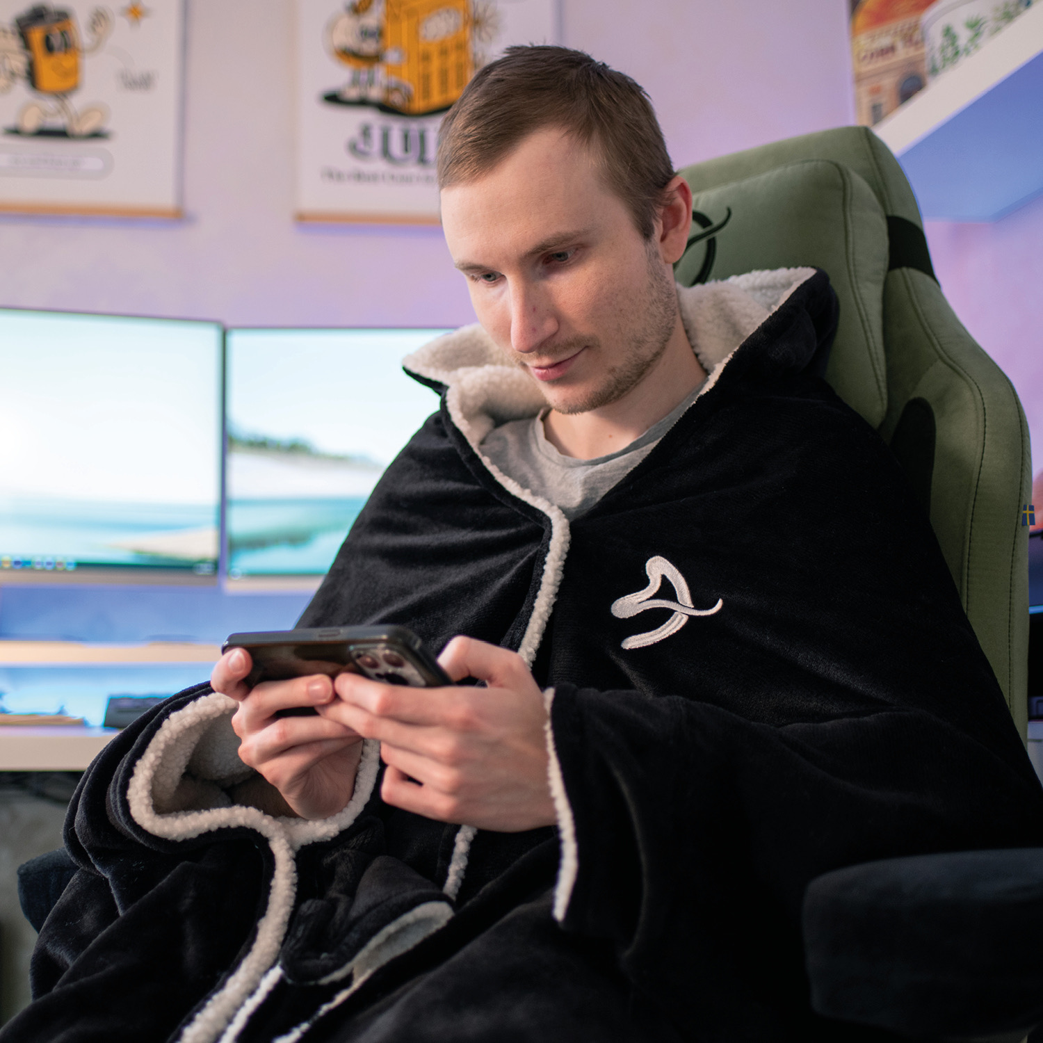 Un uomo in una coperta con cappuccio foderata di sherpa gioca al cellulare.