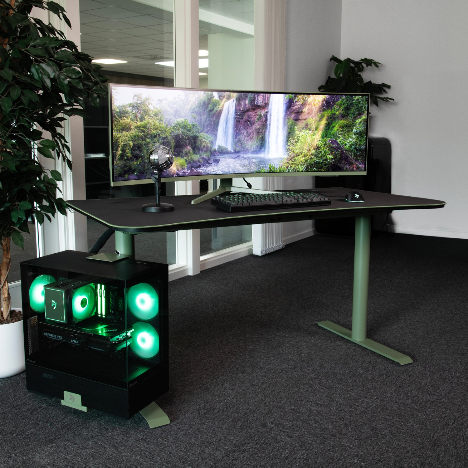 Una scrivania da gaming con un grande monitor che mostra una cascata, PC, tastiera e mouse.