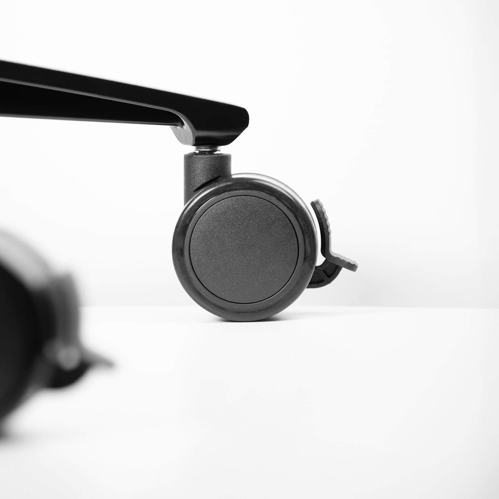 Close-up of a black caster wheel with a black lever on a white background.