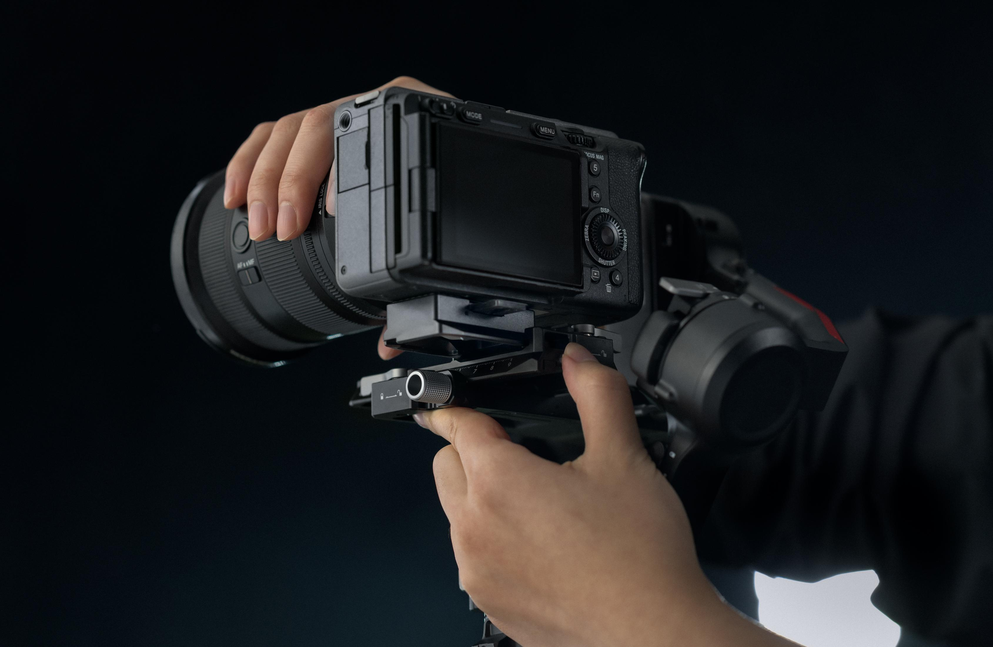 Hände stellen eine Kamera mit Objektiv auf einem Gimbal ein.