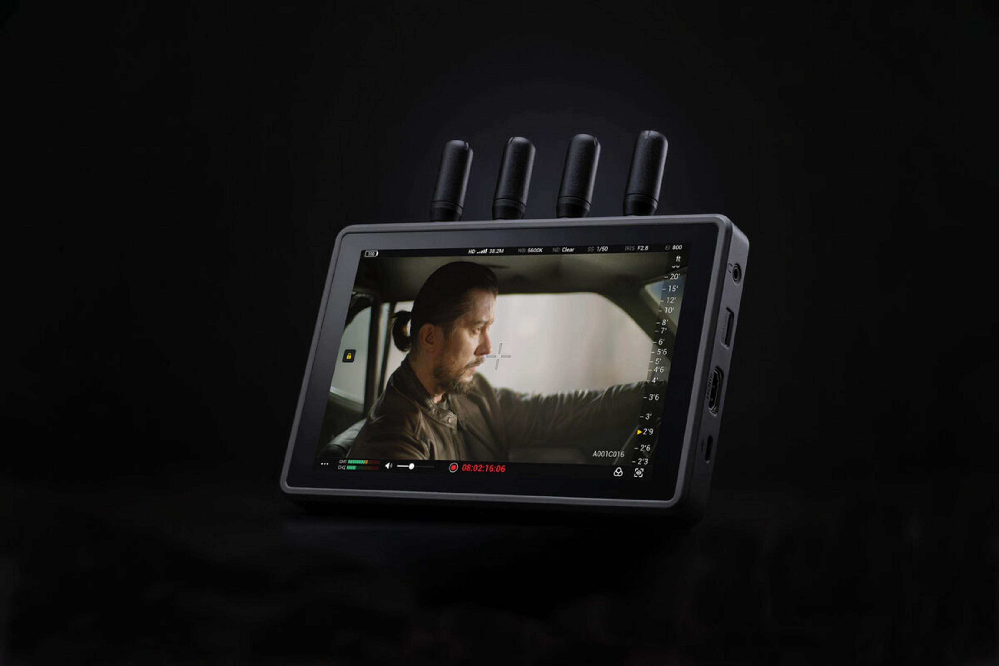 Ein Mann mit Zopf sitzt im Auto, aufgenommen auf einem Monitor.