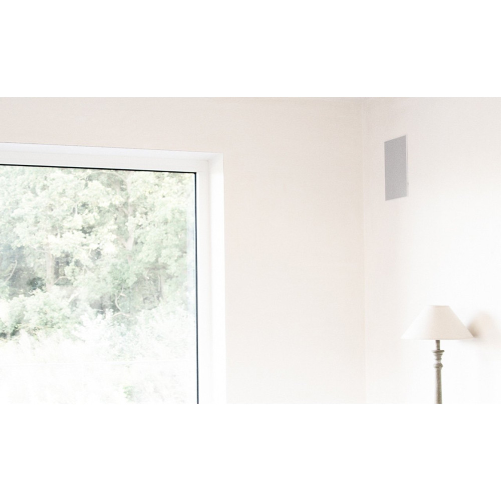Une fenêtre donne sur des arbres verts, un mur avec haut-parleur intégré et une lampe.