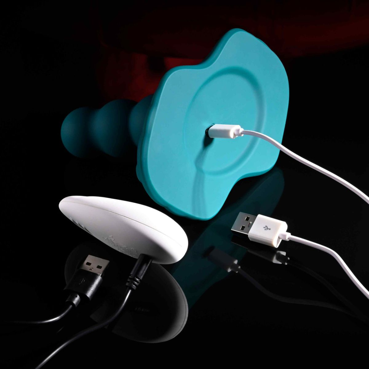 Ein türkisfarbenes Silikonspielzeug und eine weiße Fernbedienung sind per USB-Kabel verbunden.