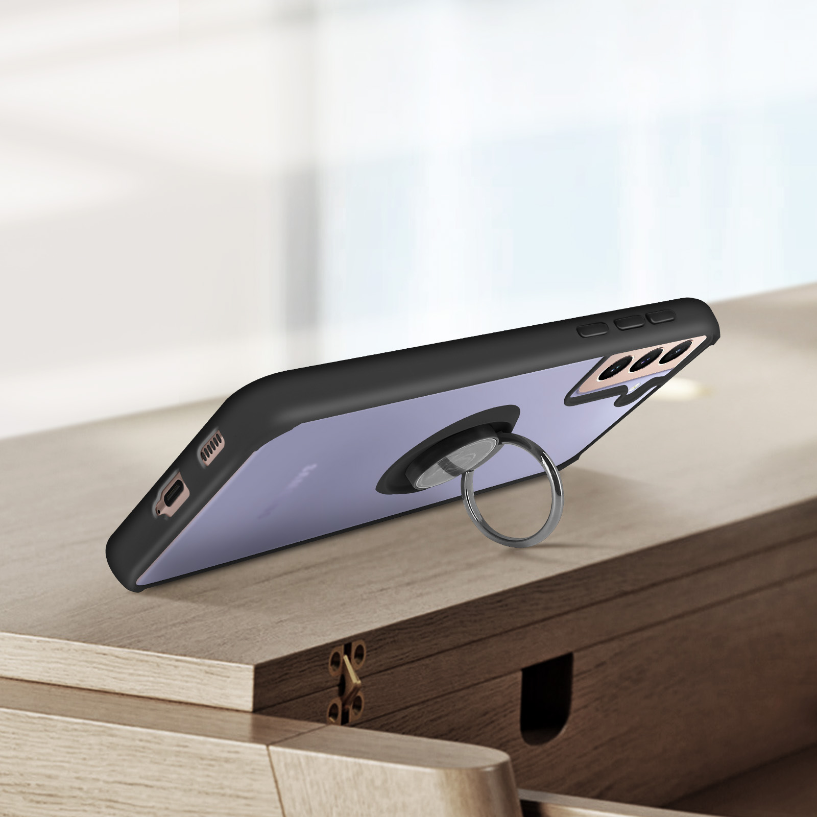 Un smartphone avec un étui violet et un support anneau repose sur une table en bois.