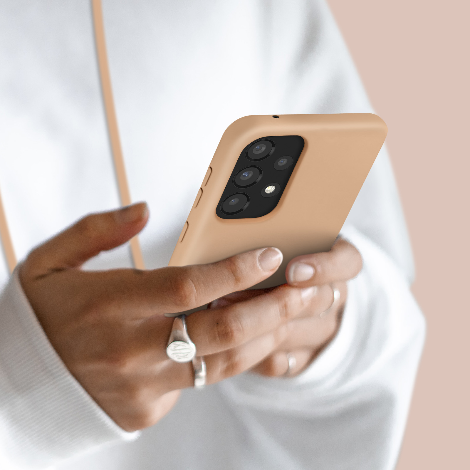 Une personne tient un smartphone brun clair avec quatre caméras.