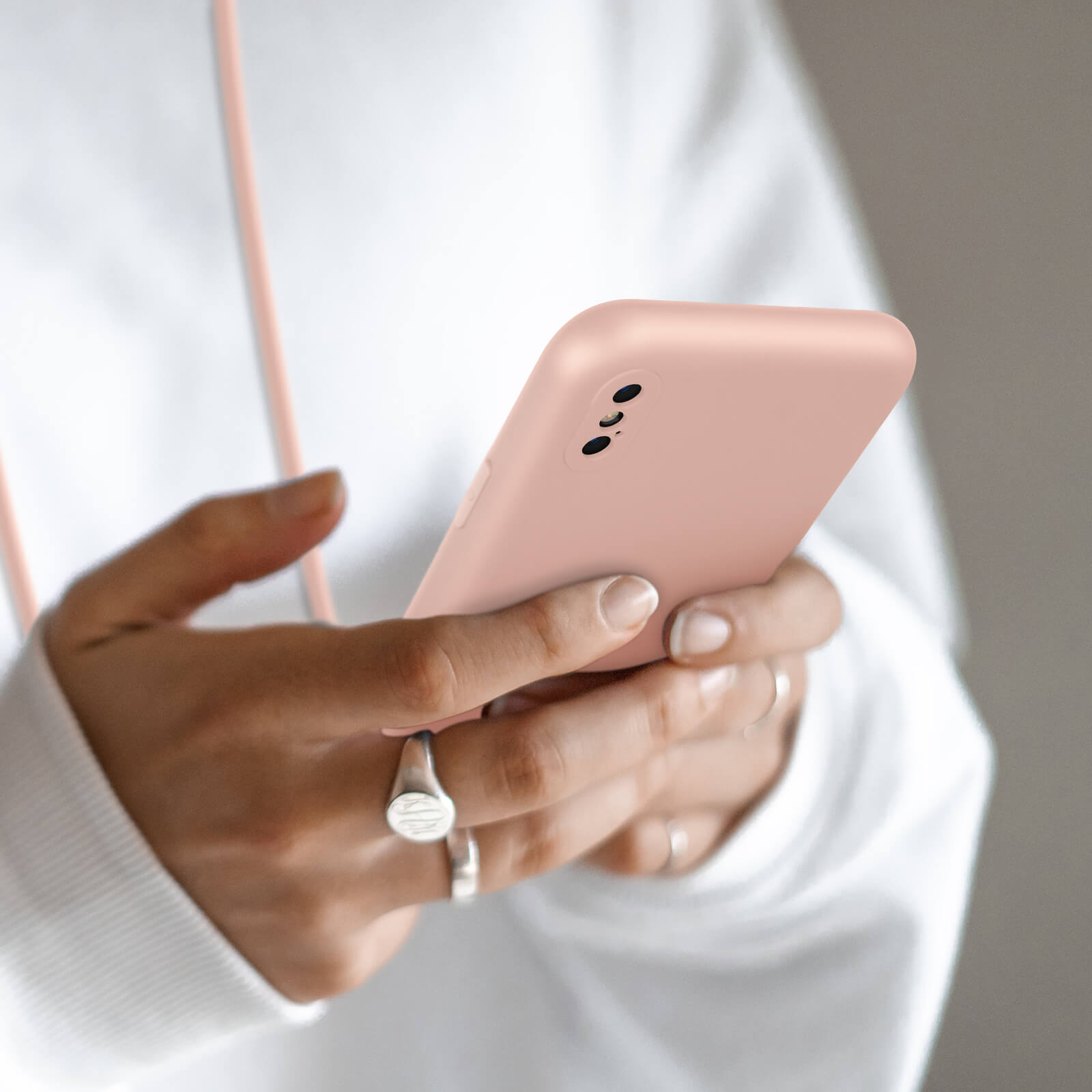 Une personne tient un smartphone rose avec trois caméras.