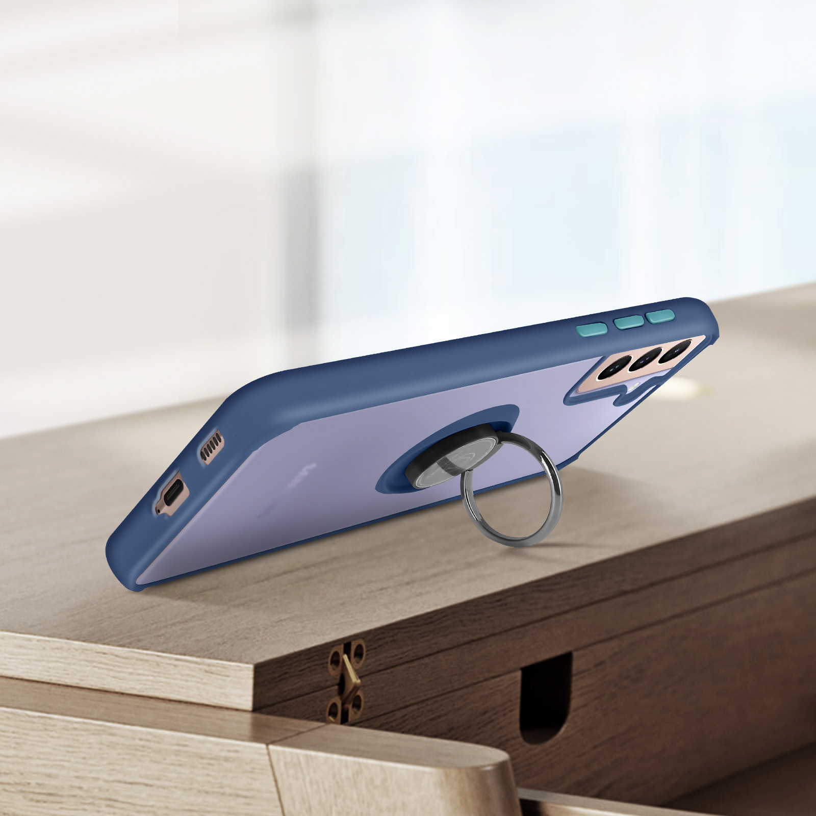 Custodia blu scuro per telefono con anello portadita su tavolo di legno.