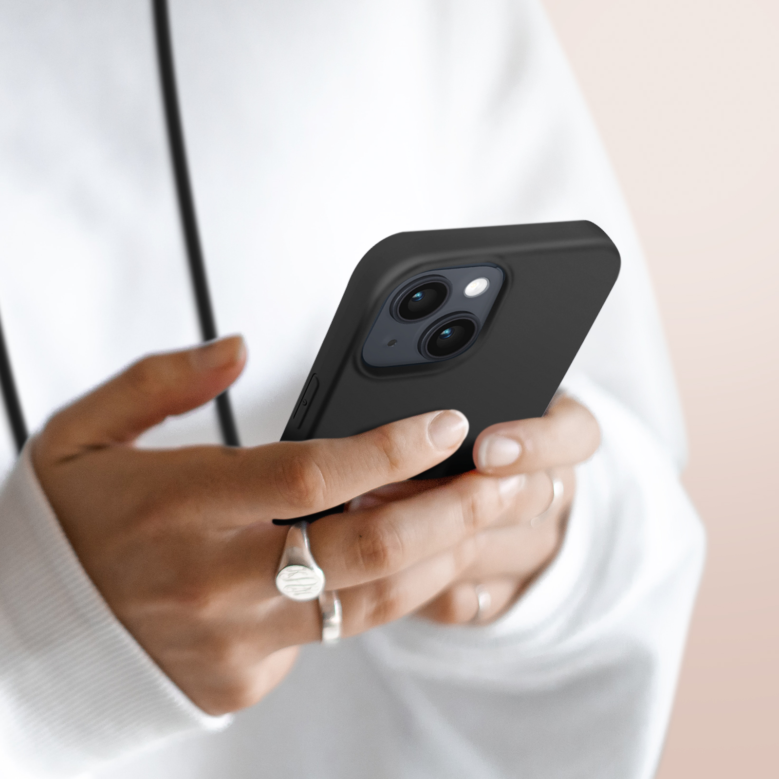 Een persoon in een witte hoodie houdt een zwarte smartphone met twee camera's vast.