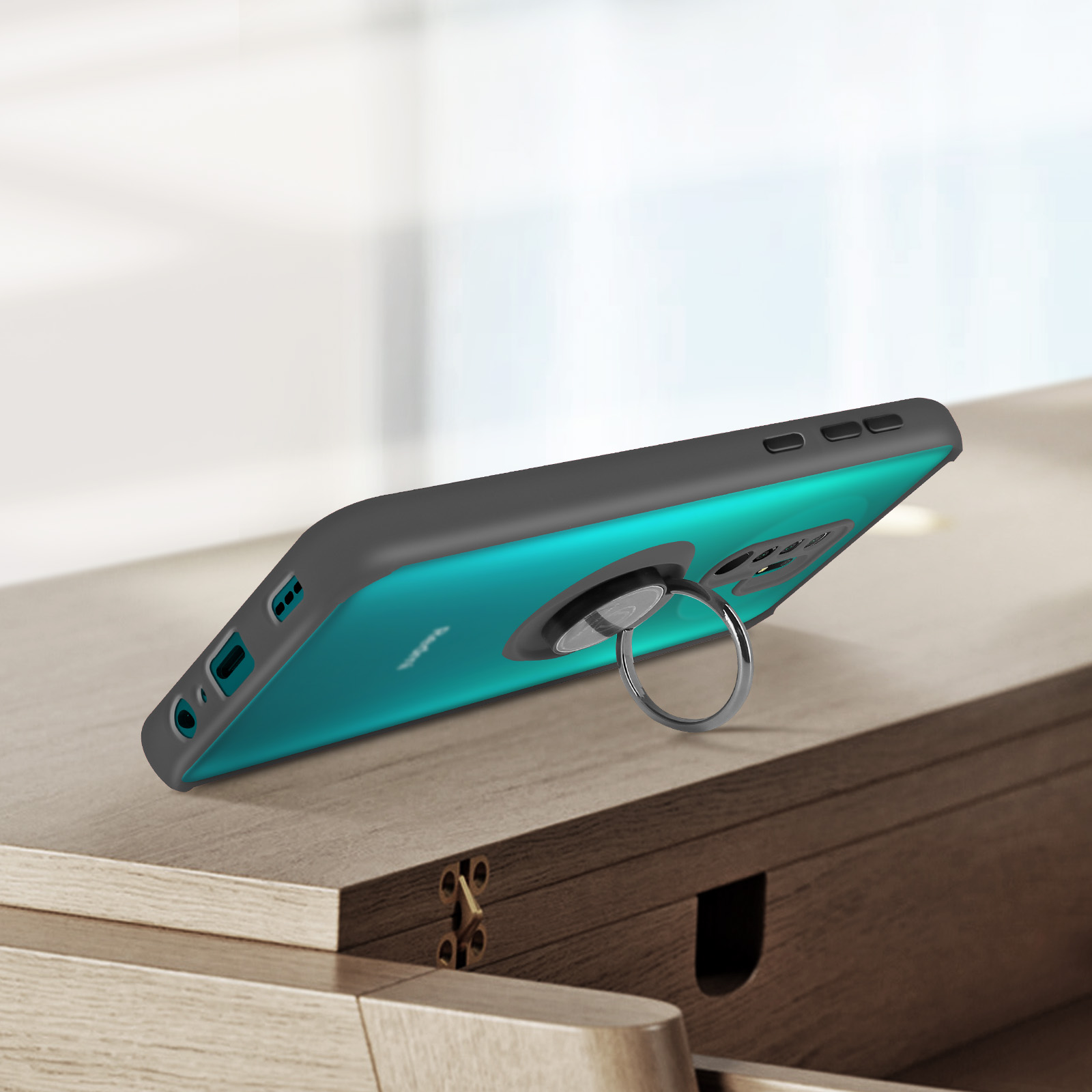 Uno smartphone verde acqua con custodia grigia e anello portacellulare appoggiato su legno.