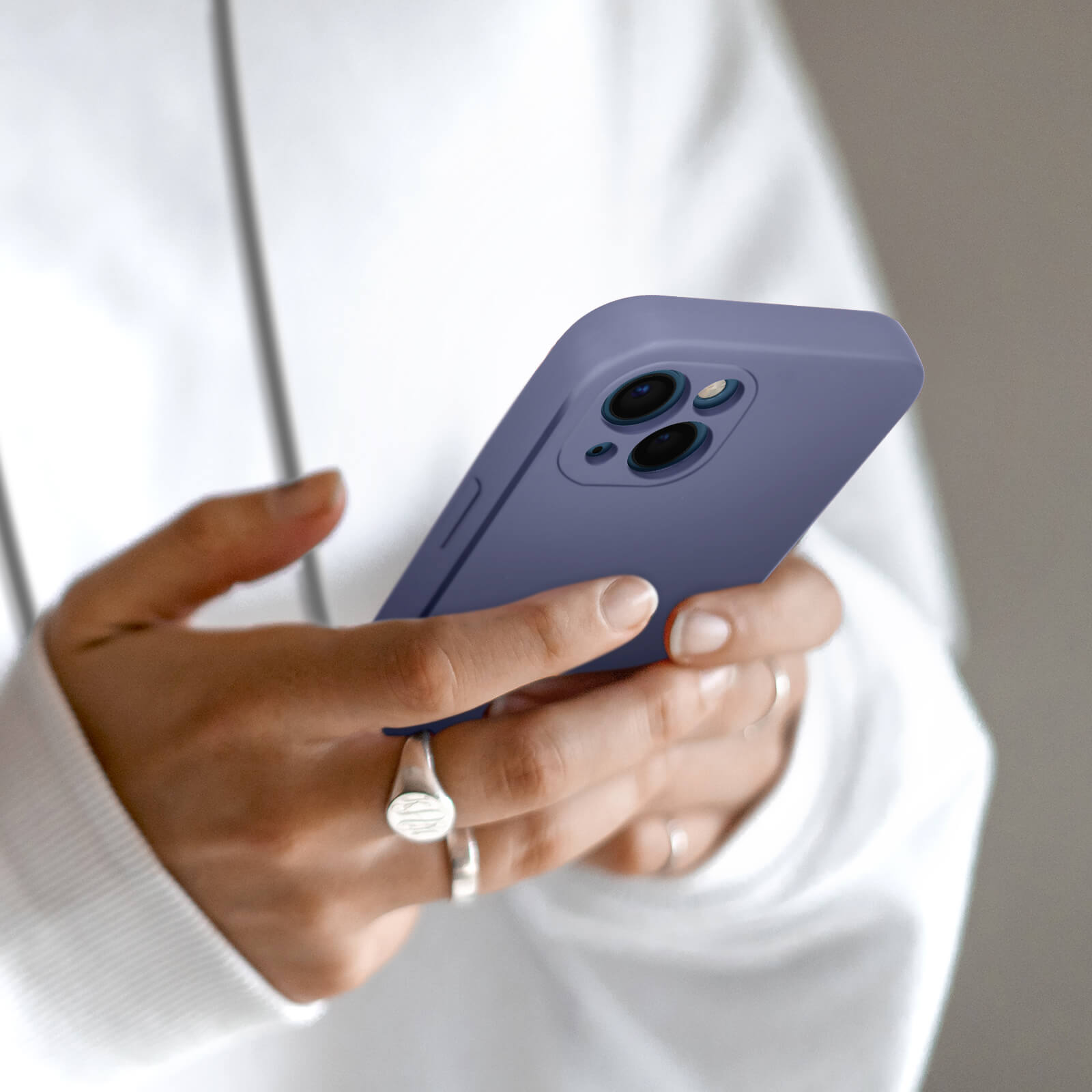 Mani che tengono un telefono viola con tre fotocamere.
