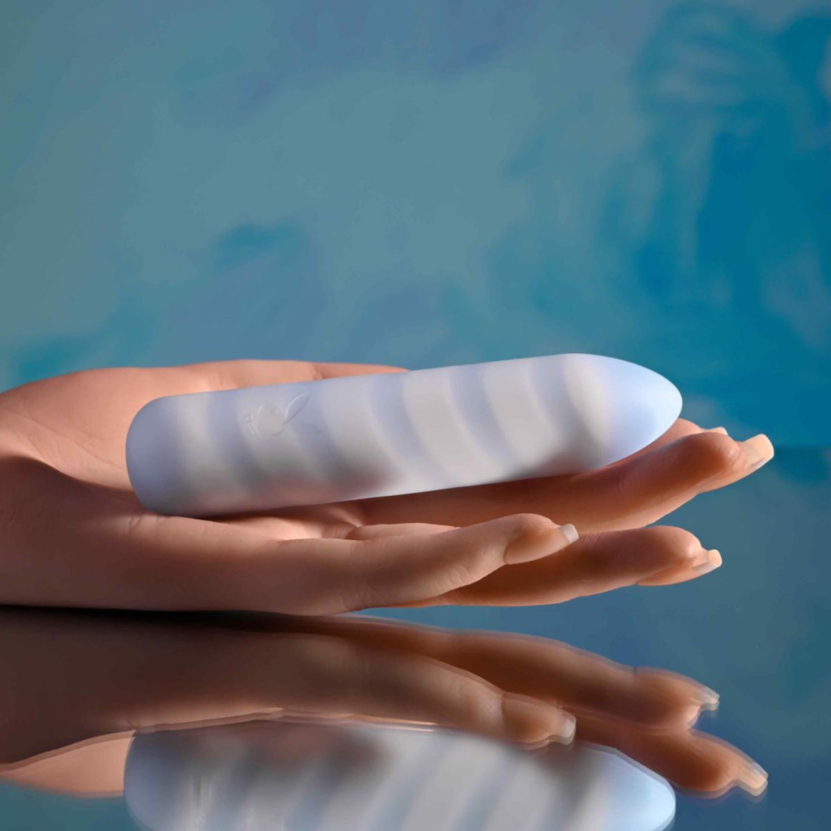 Eine Hand hält ein gestreiftes, weiß-blaues Objekt vor einem blauen Himmel.