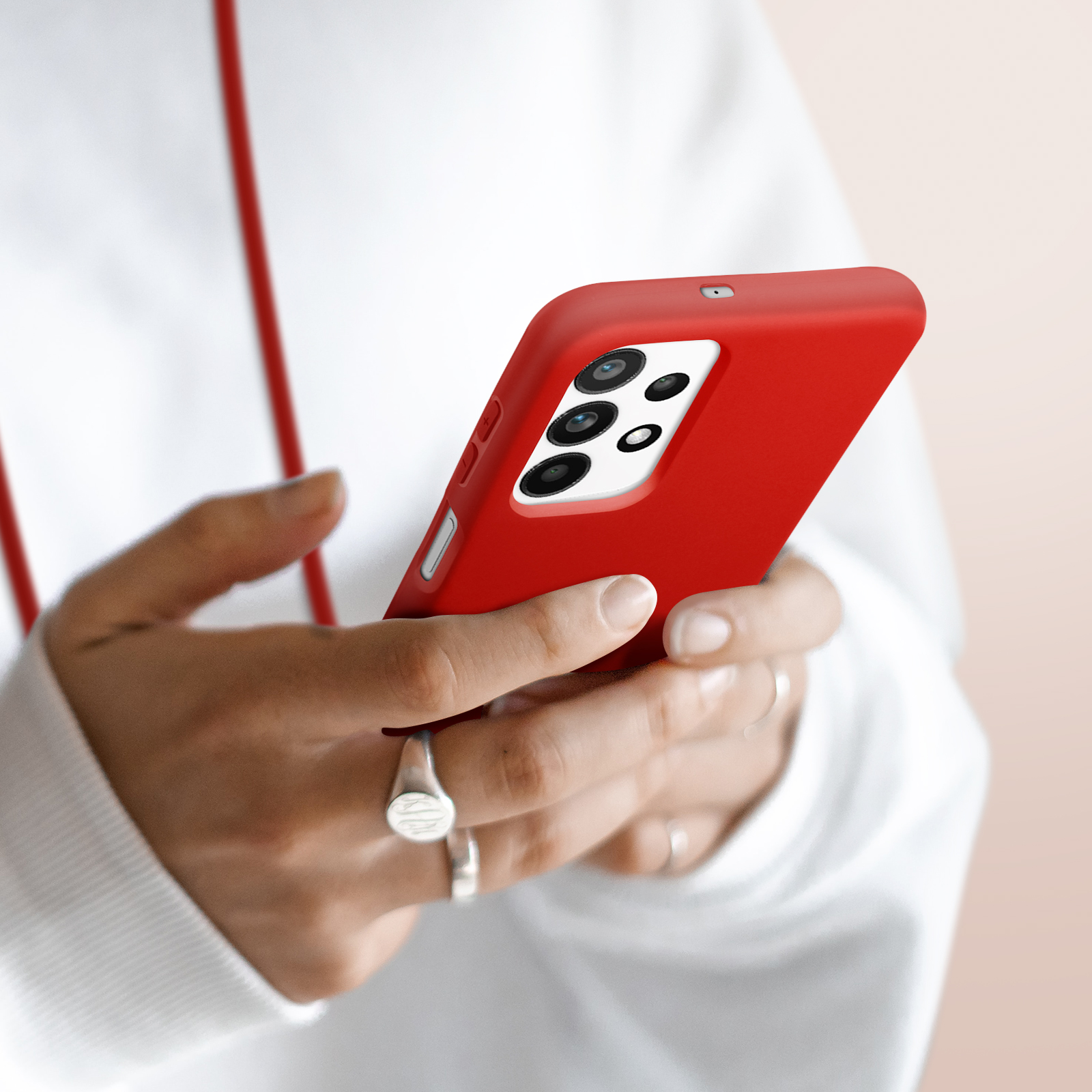 Handen houden een rode smartphone met een camerasysteem met vier lenzen vast.