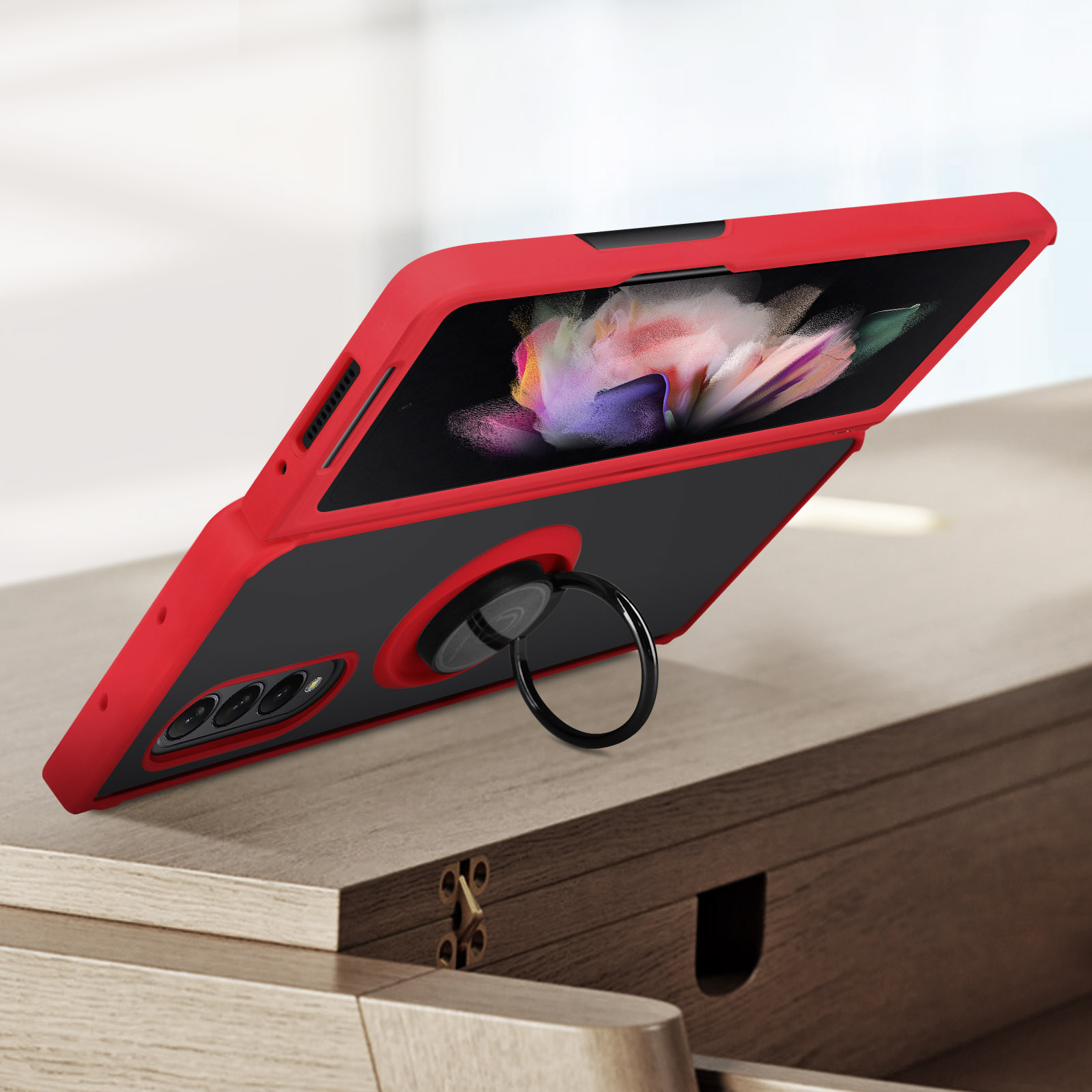 Coque de téléphone rouge avec support anneau et caméras sur table en bois.