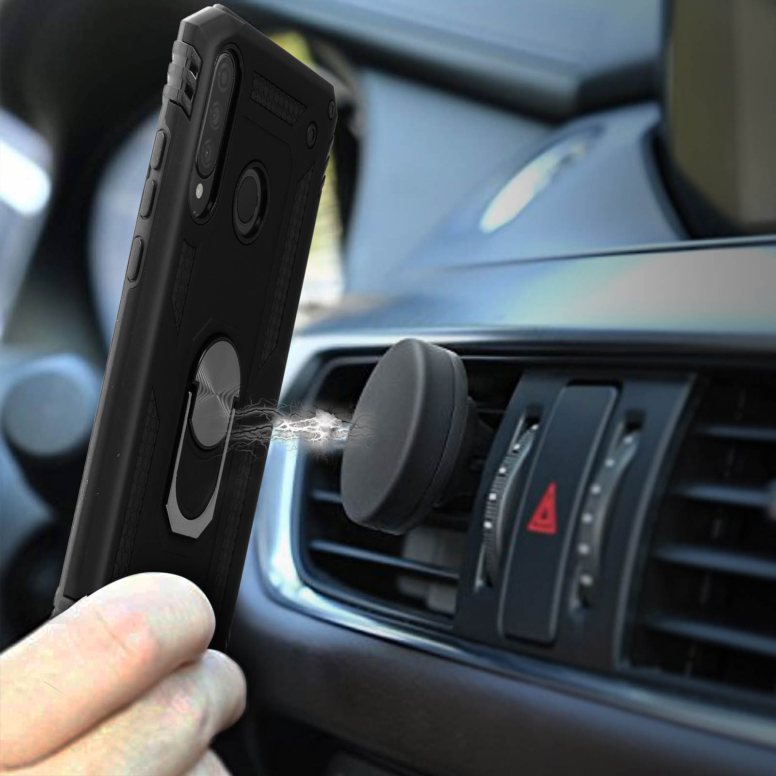 Téléphone noir avec support bague tenu par la main près d'une aération de voiture.